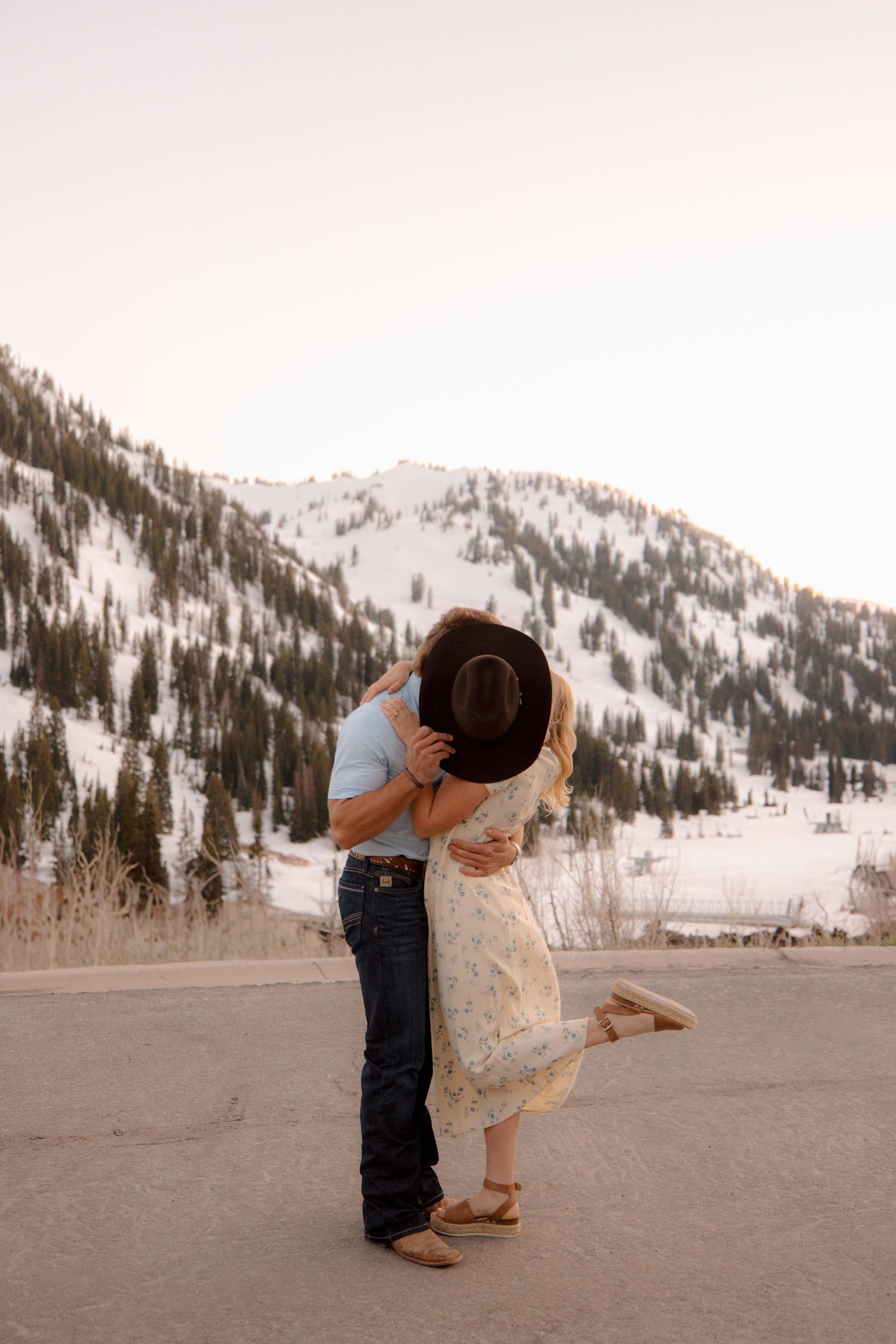 Two people dance together in a romantic embrace against a scenic snowy mountain backdrop.