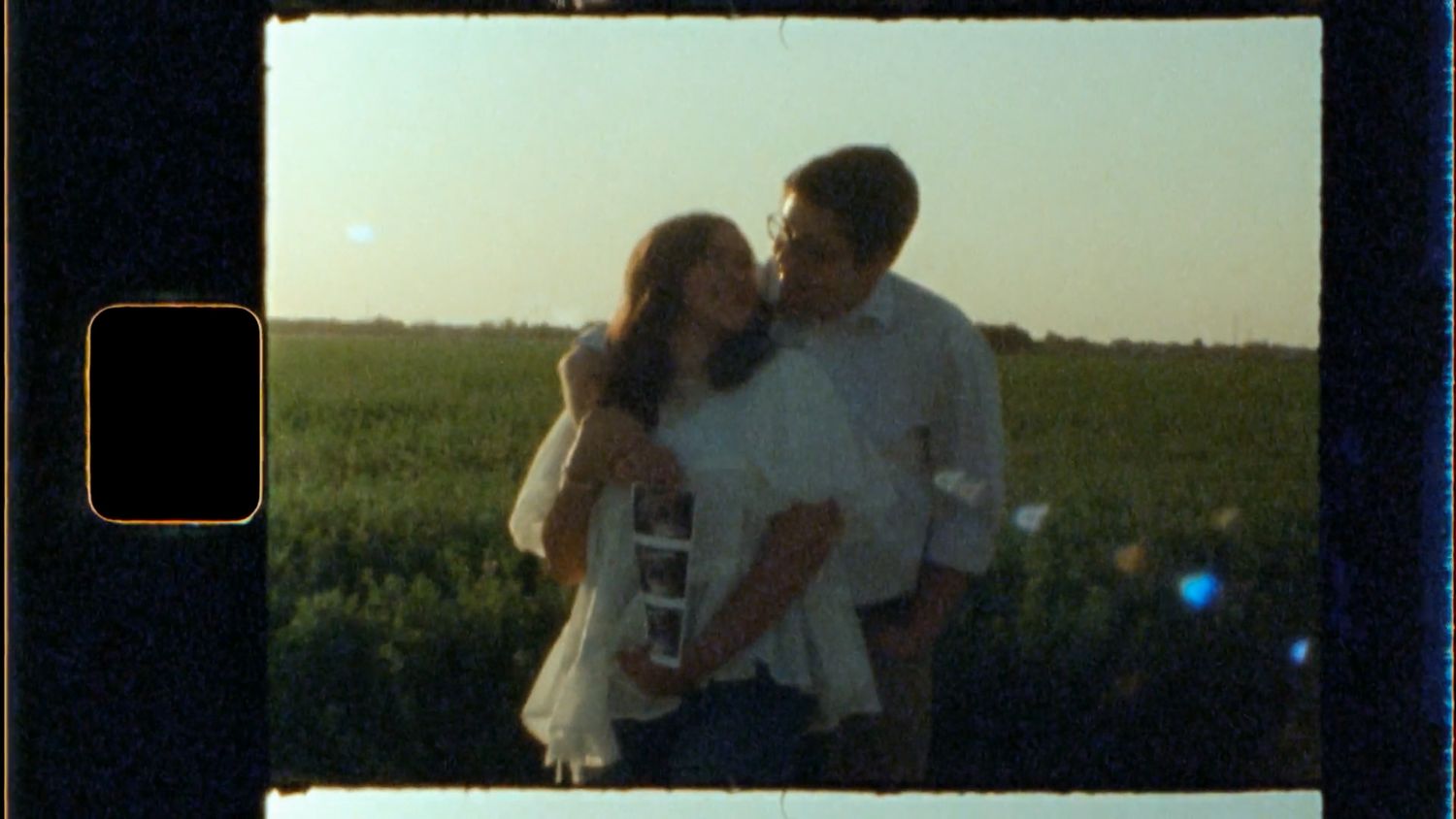 A romantic silhouette of a couple embracing in a meadow against the soft sunset sky.