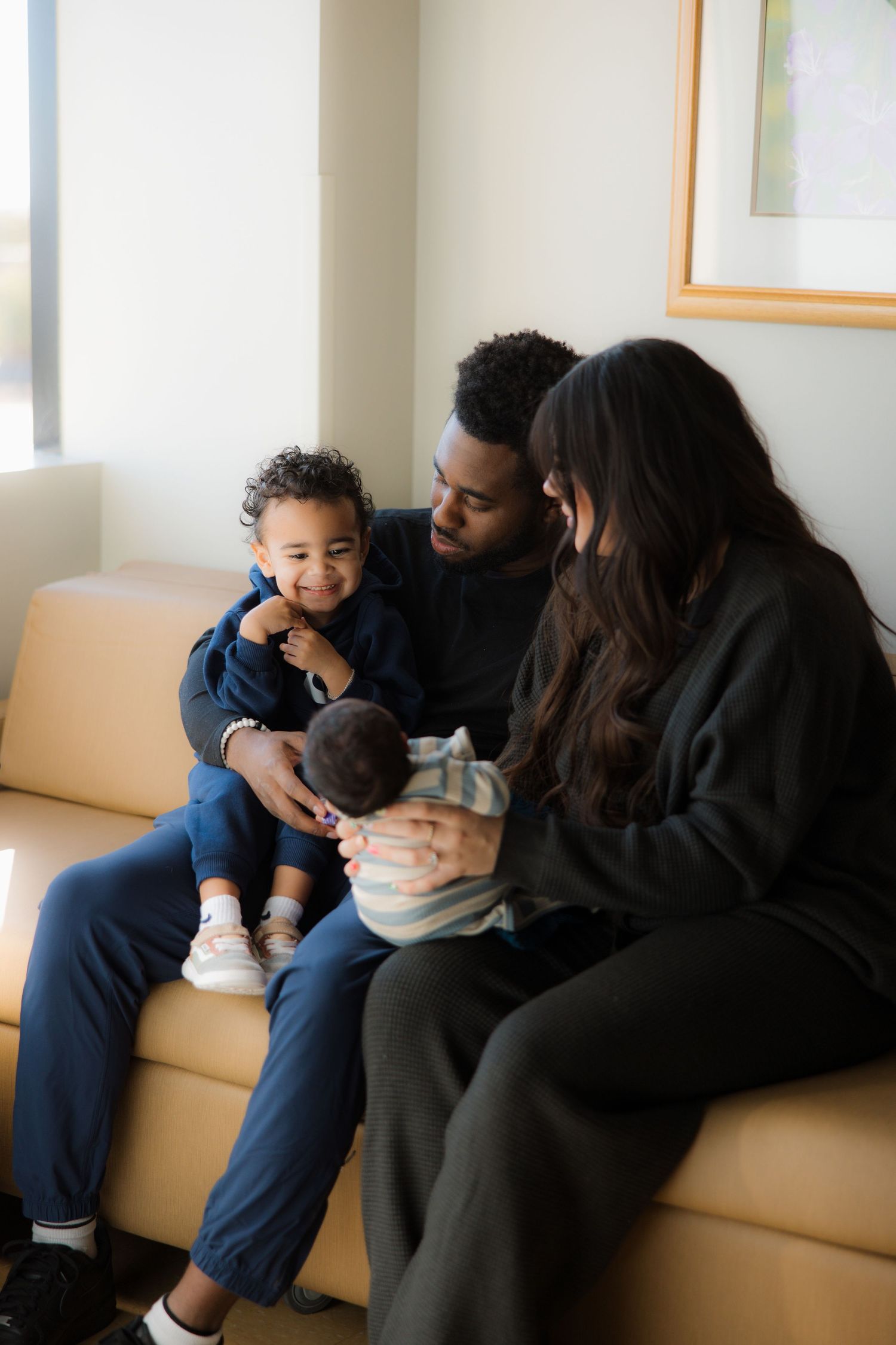A loving family moment showing affection and closeness while sitting together on a beige couch at home.