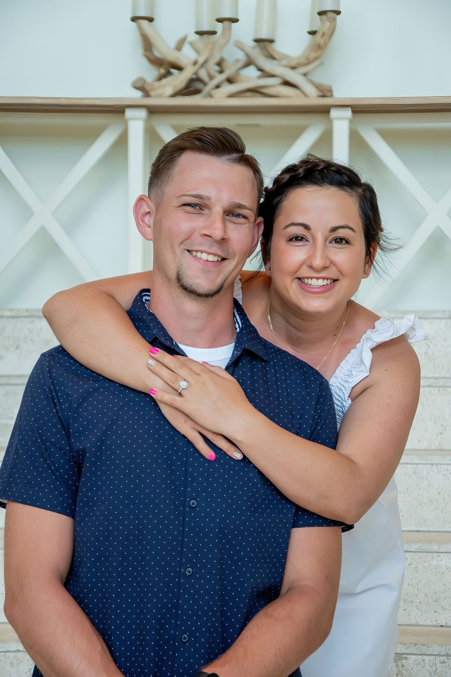 Couple in navy blue polka dot shirt and white dress embrace in a romantic outdoor photoshoot series.