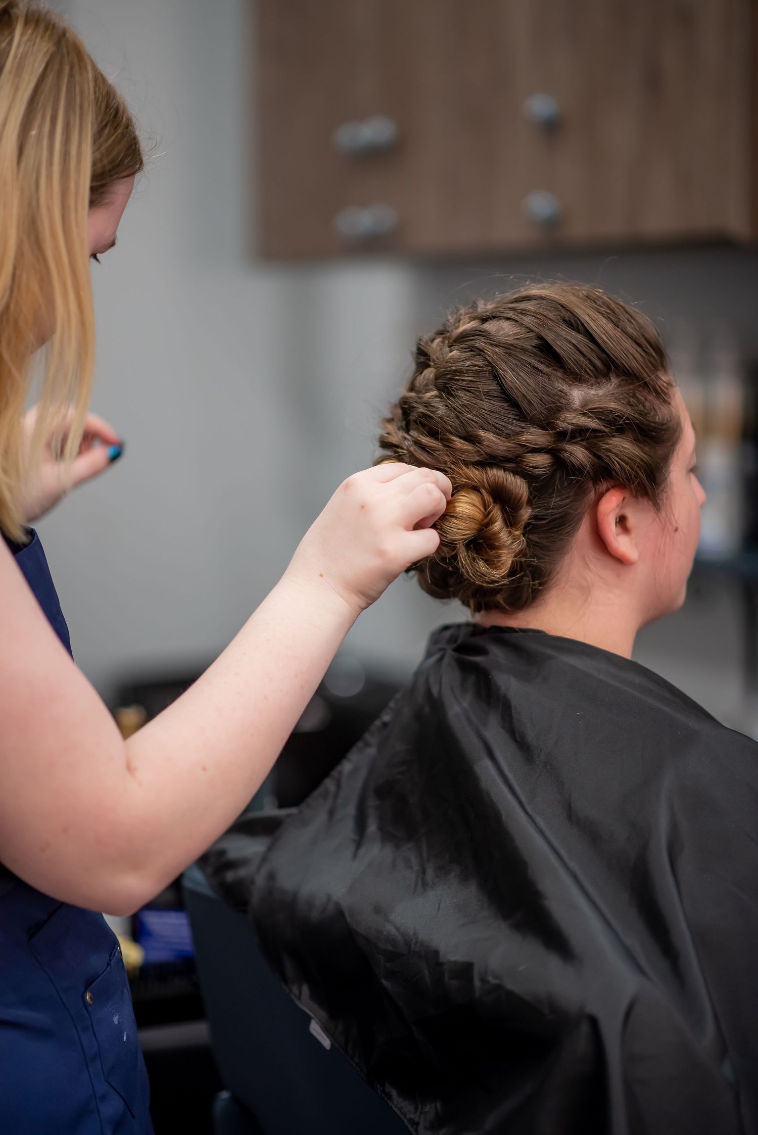 A blonde stylist finalizing a bridal style at Vazul hair Artistry, an Ocala, FL based salon.