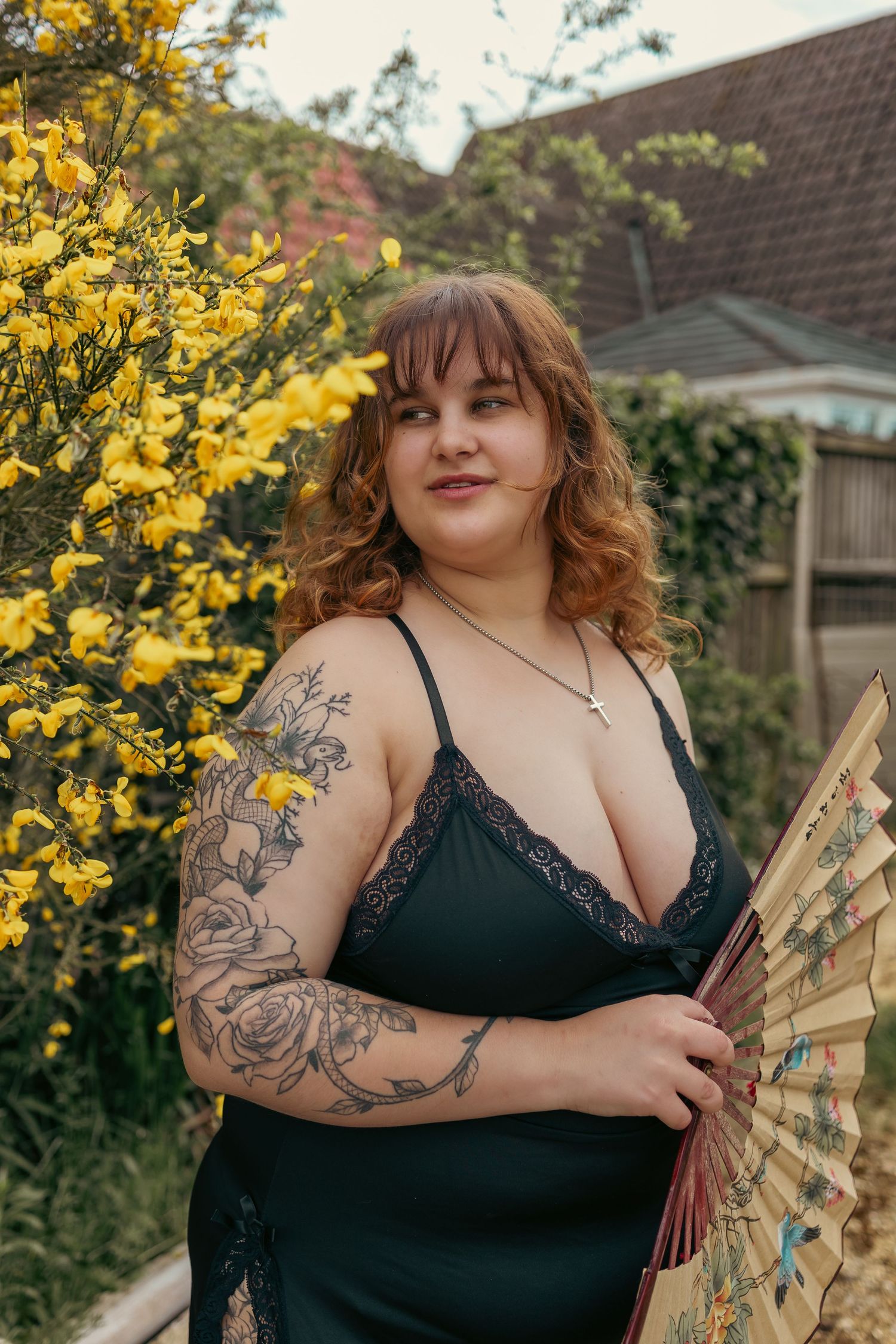 Tattooed, plus size woman posing with a Japanese fan amongst some flowers, outdoors confidence boosting boudoir photography Suffolk