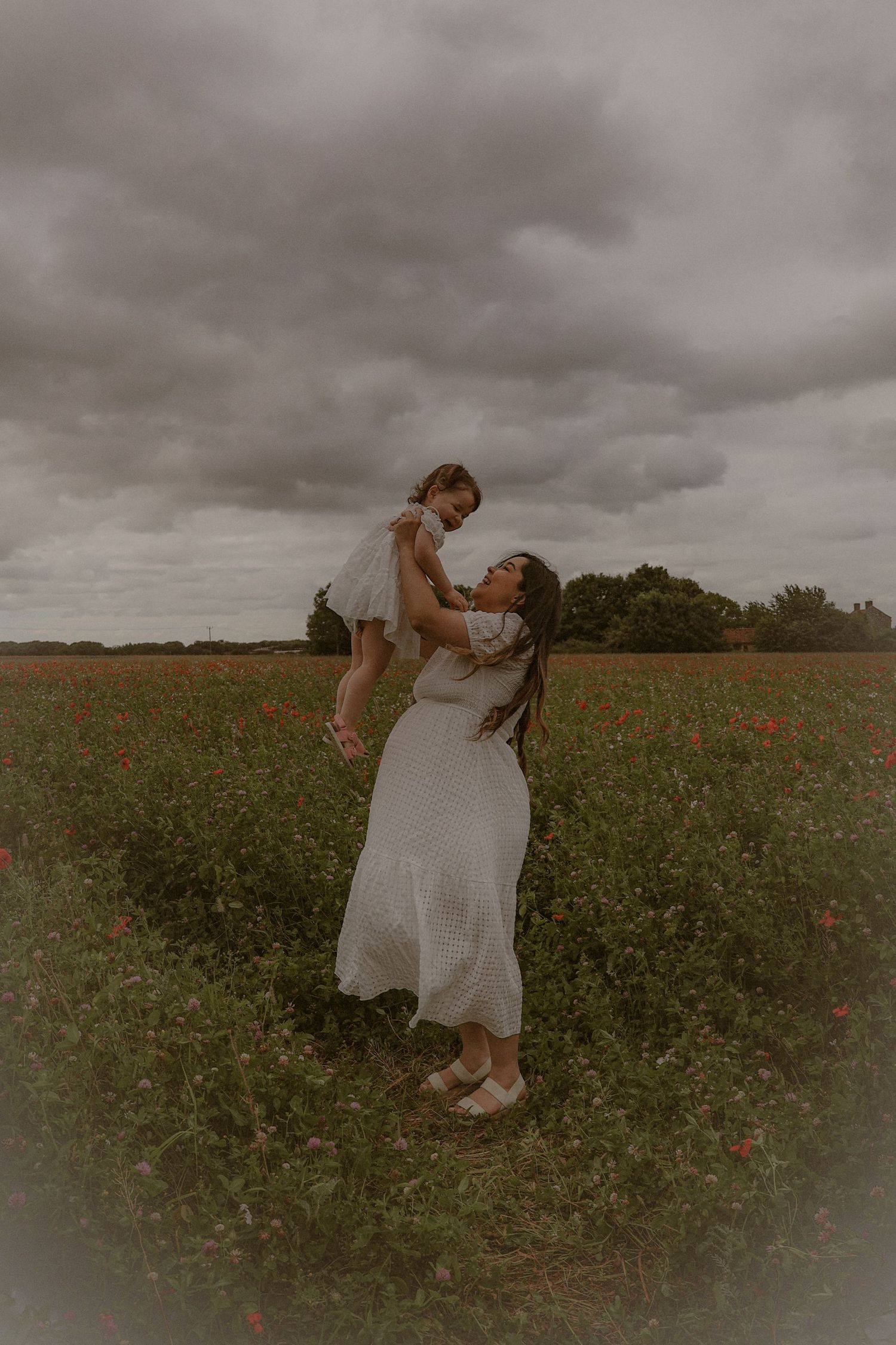 cinematic,  portrait of woman and her little girl  in a wild flower field in Suffolk, captured by Untamed Muses