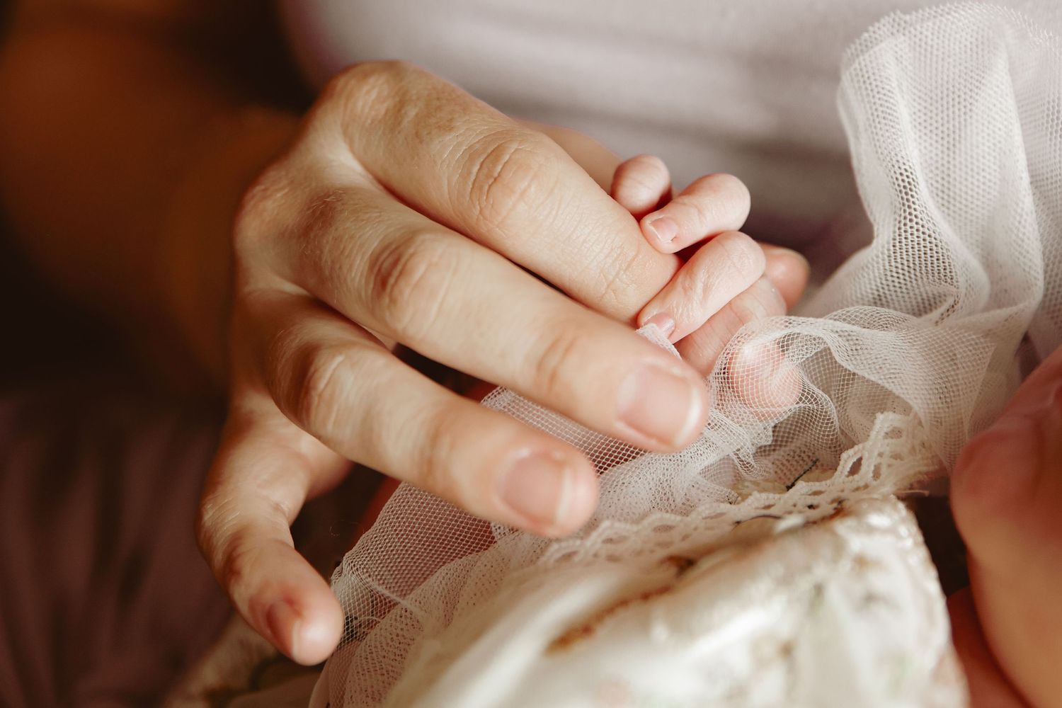 Close up detail of mother and newborn daughters hand , during a natural newborn photoshoot by Untamed Muses in the comfort of their own home