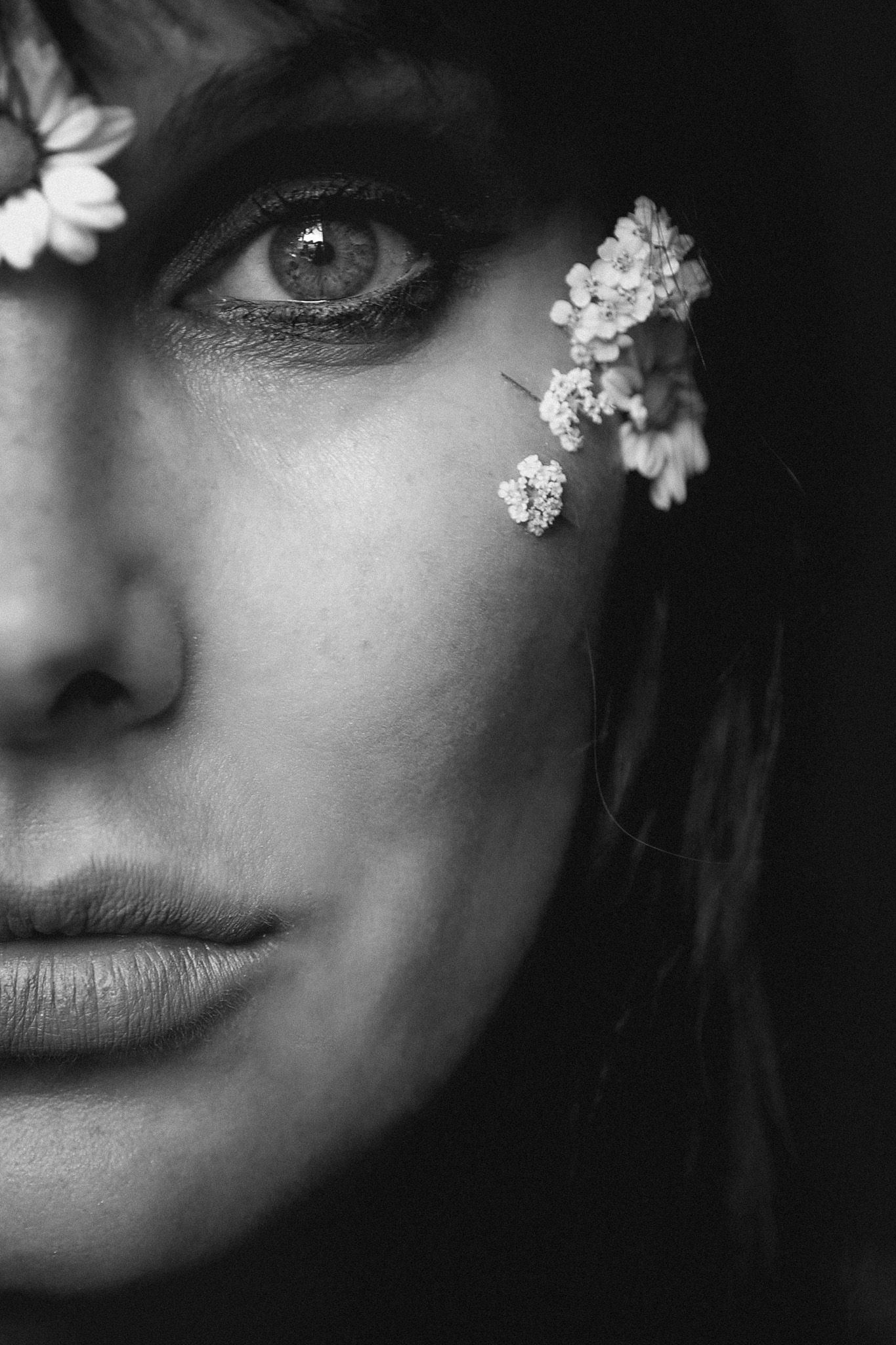monochrome, close up to one eye and some small flowers of side of faces of a woman