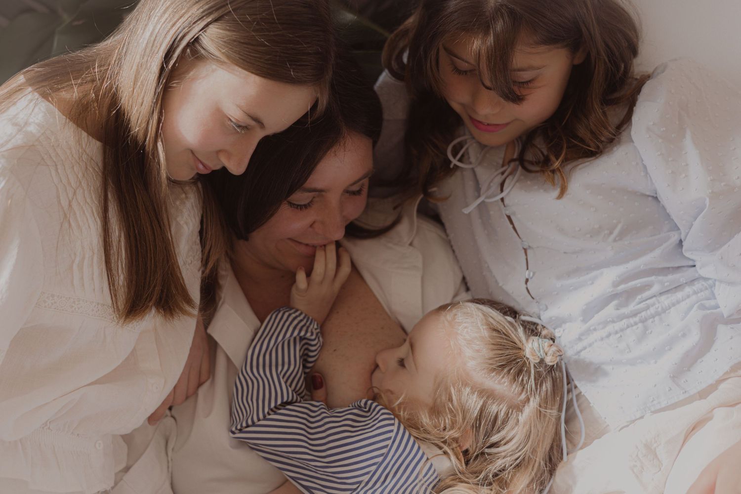 close up portrait during motherhood photoshoot in a Norfolk home, mother and her three daughters sharing a tender moment, natural light