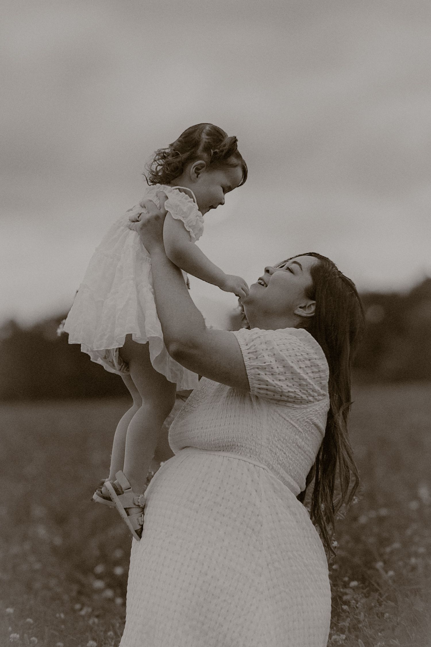 cinematic, monochrome portrait of woman and her little girl  in a wild flower field in Suffolk, captured by Untamed Muses
