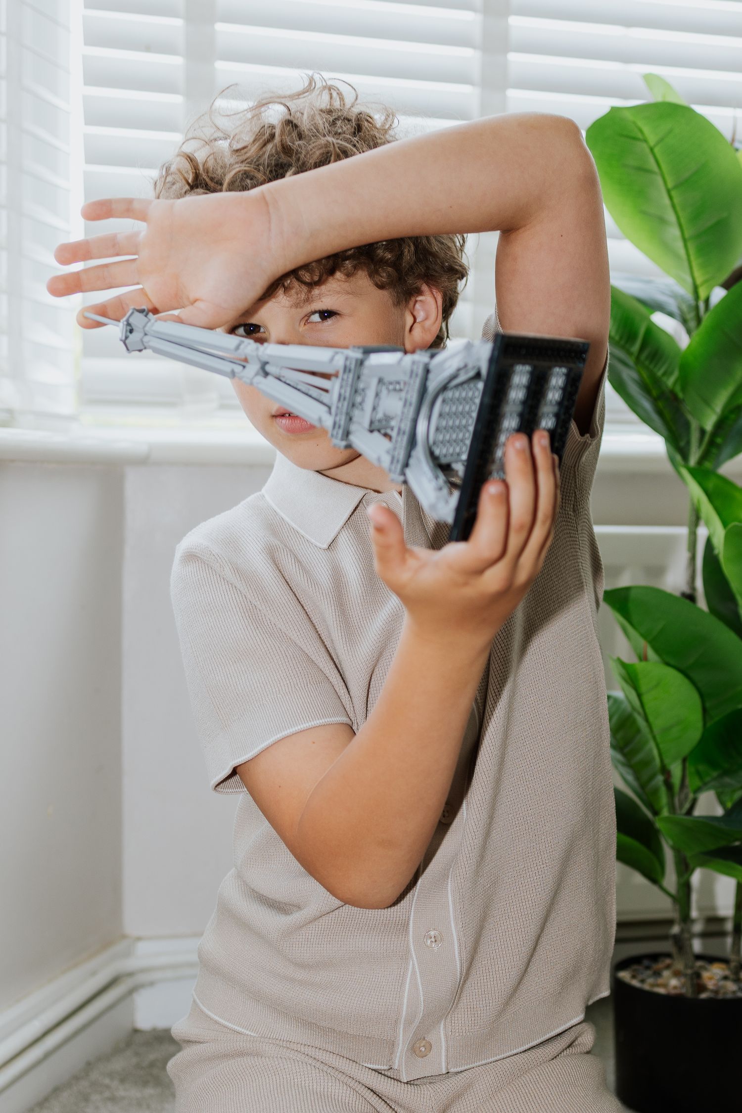 Portrait of child playing with lego Eiffel Tower, natural light, at home lifestyle session