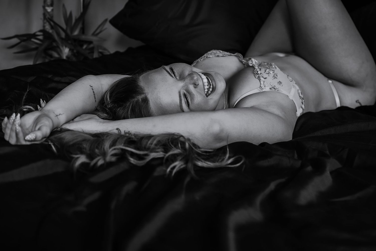 Monochrome boudoir portrait woman laughing out loud spilling with joy in Norfolk, empowerment photography by Untamed Muses