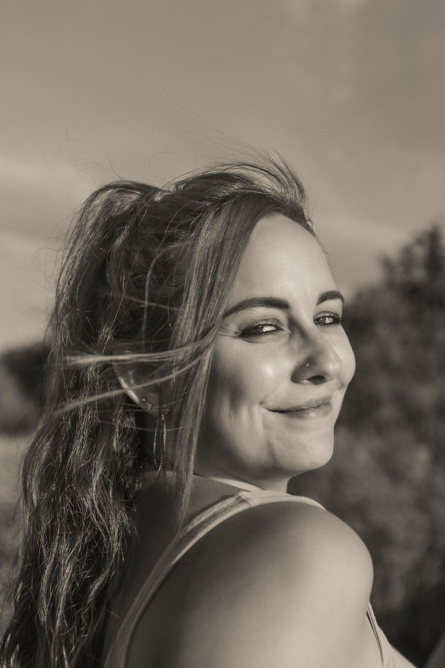 Monochrome portrait of woman smiling, hair windwepts, sun in her face