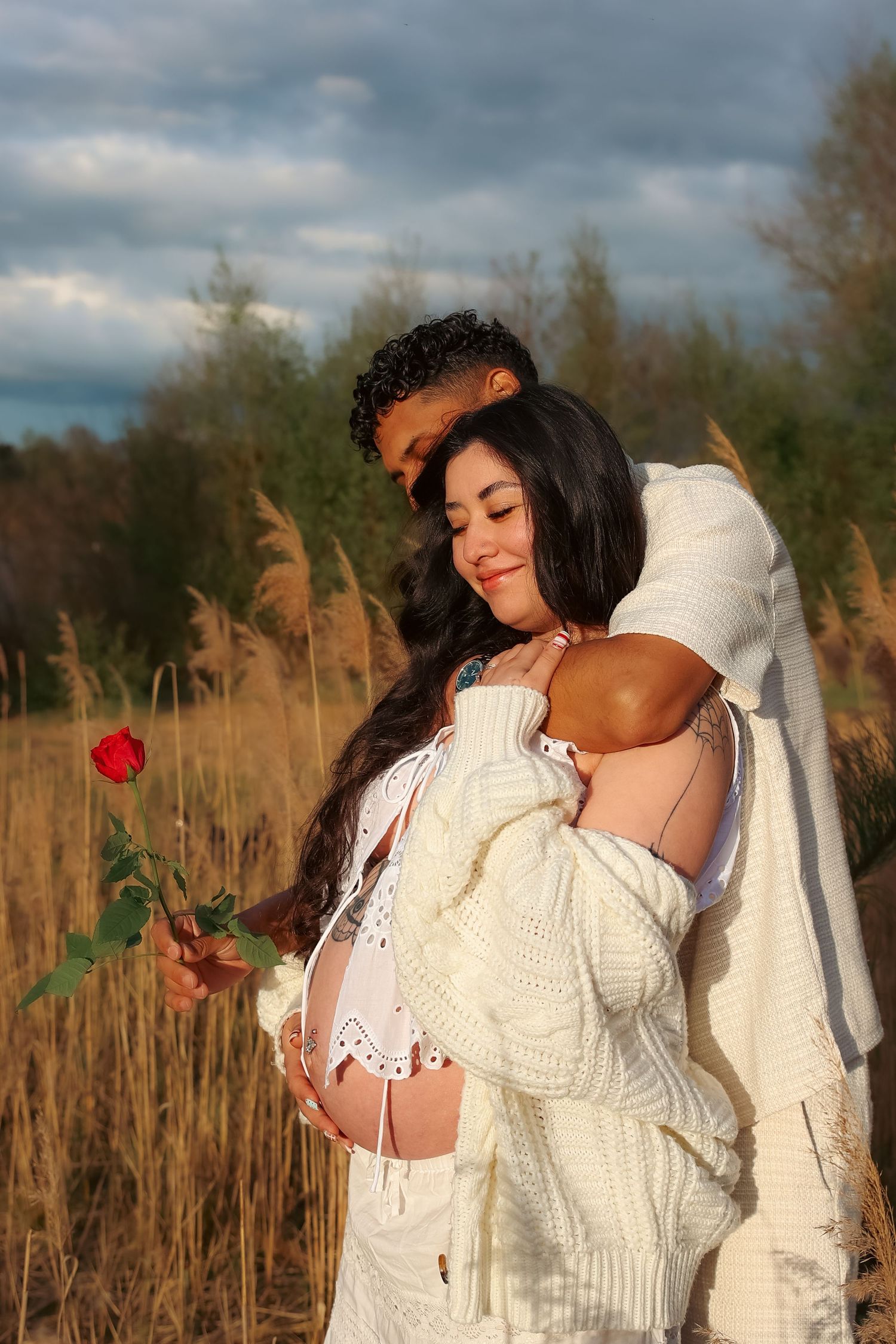 maternity photoshoot with untamed muses photography , outdoors during a spring evening in Norfolk, Safe in her husbands arms at sunset