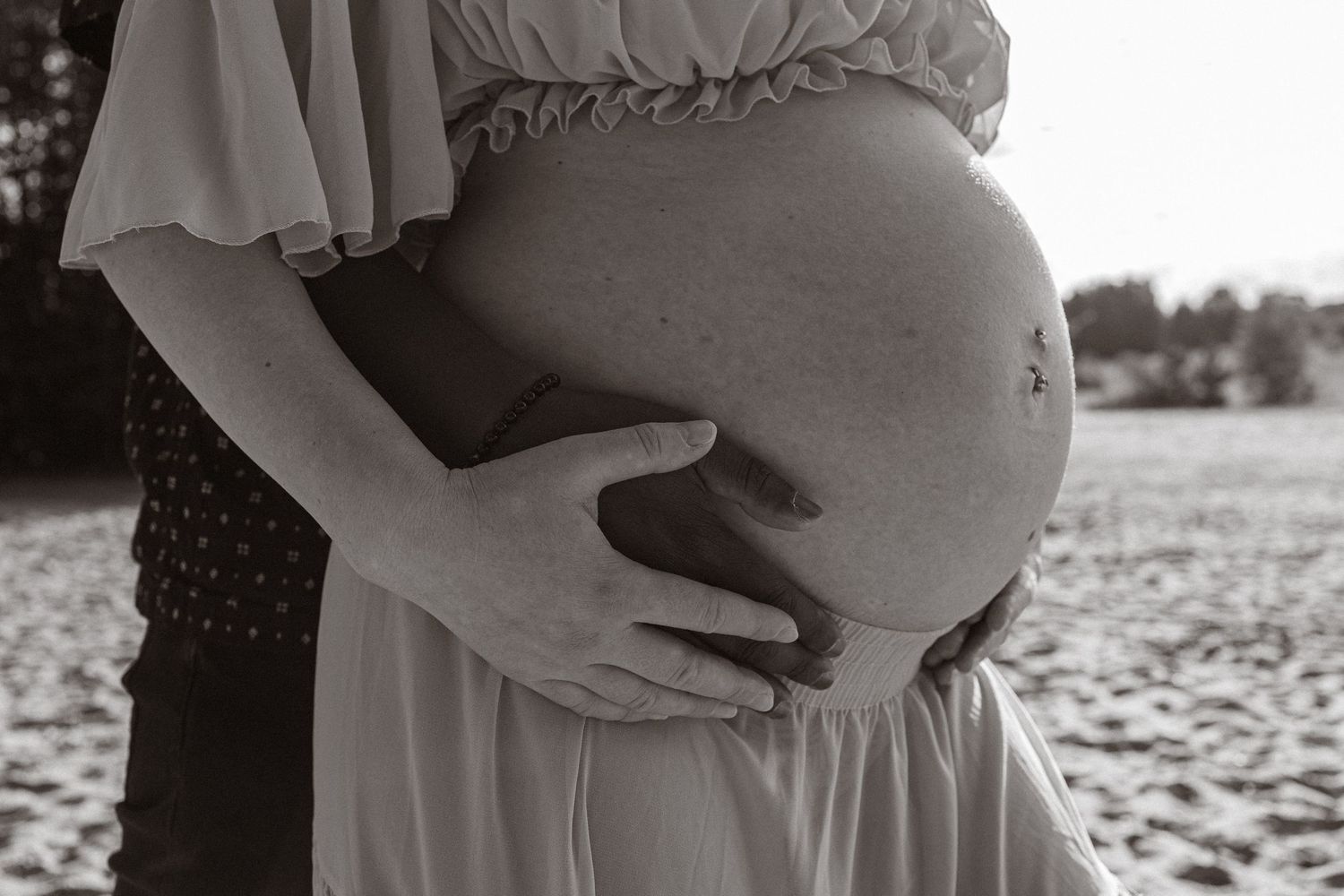 close up detail from maternity shot in lyngford  , biracial couple, hands cradling bump, monochrome, natural light
