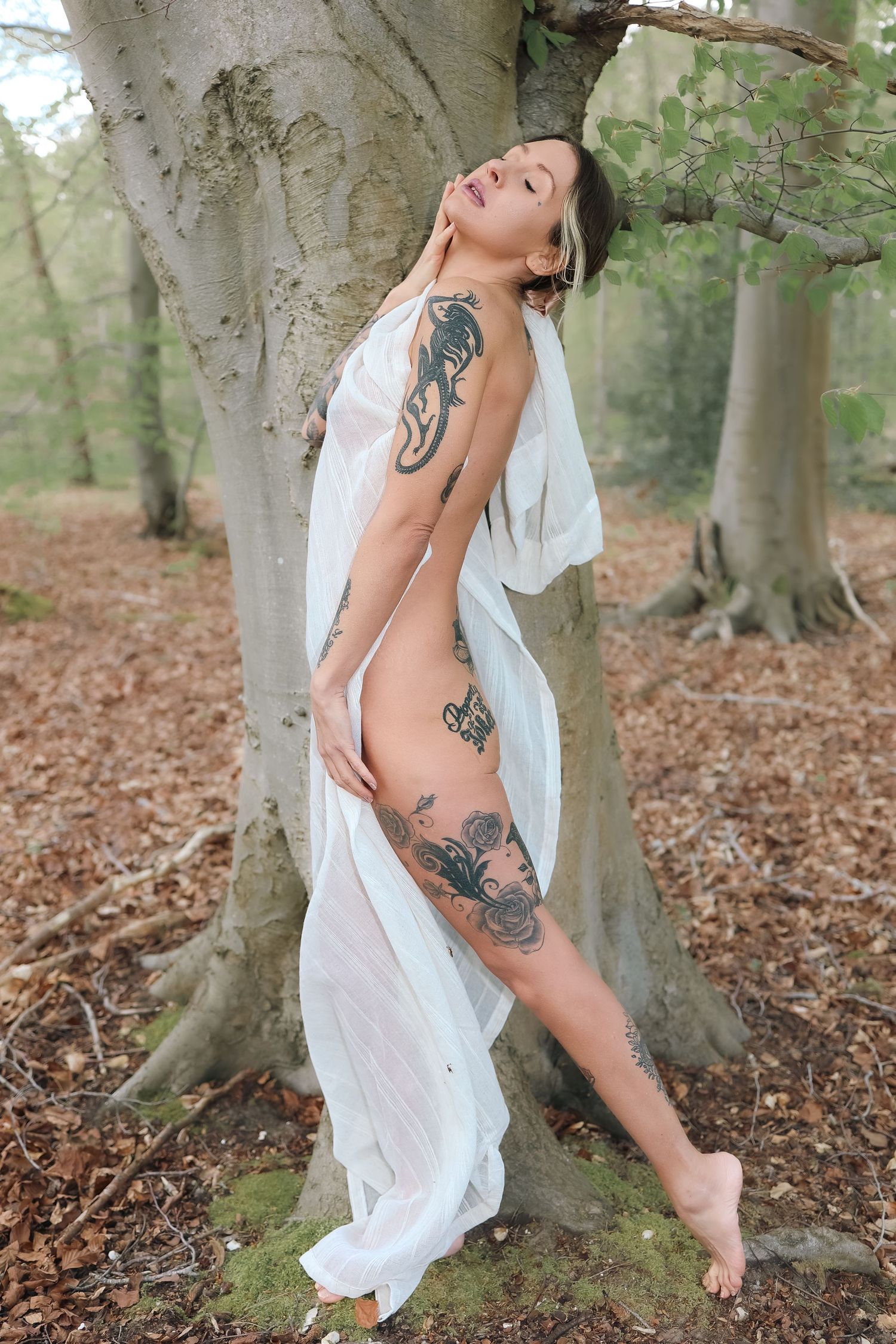 Outfdoors Empowerment boudoir photography in Thetford, lady posing by a tree, graceful and elegant , tattooed and confident
