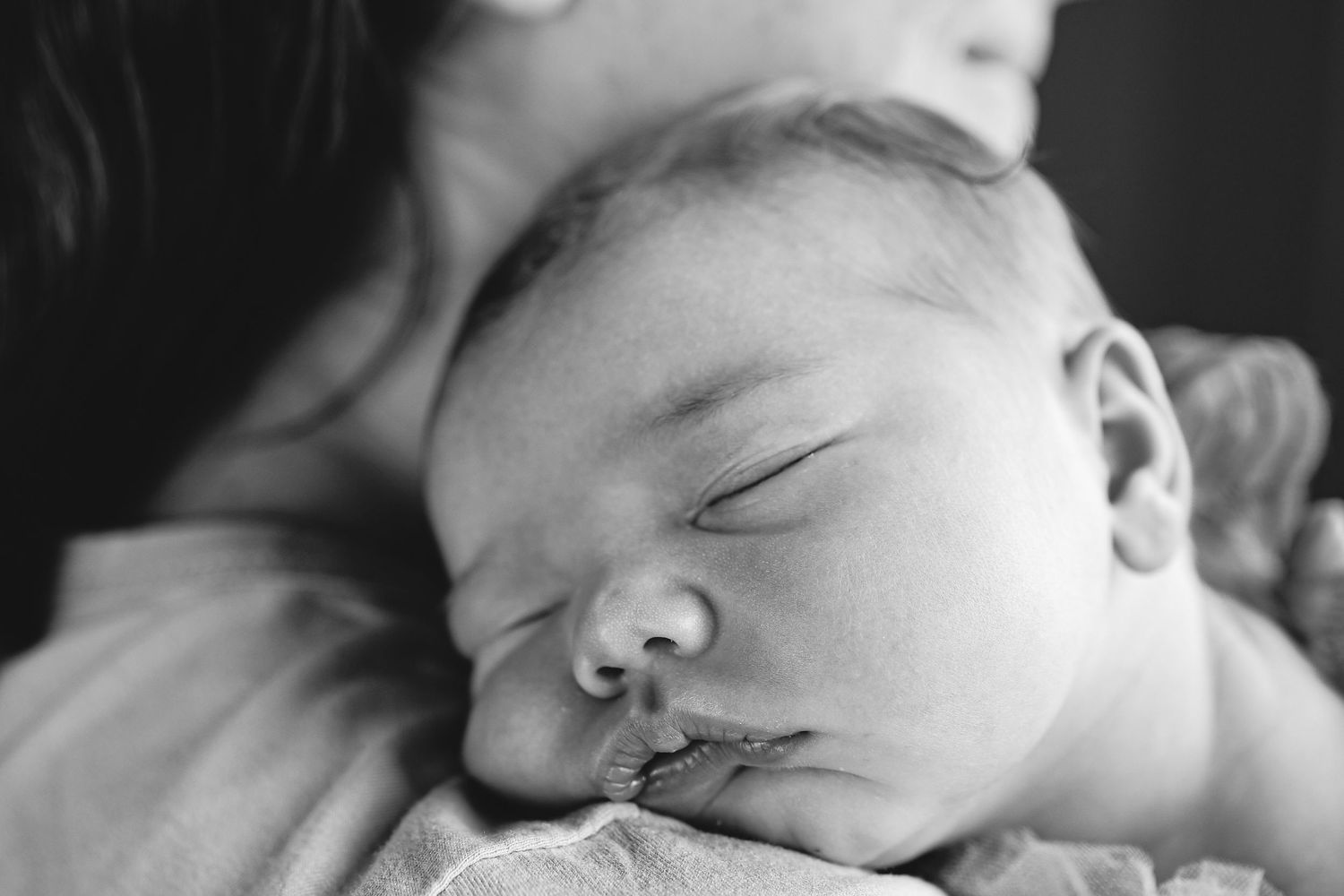 Close up portrait in monochrome of newborn asleep peacefully resting on mums shoulder during a natural newborn session by untamed muses