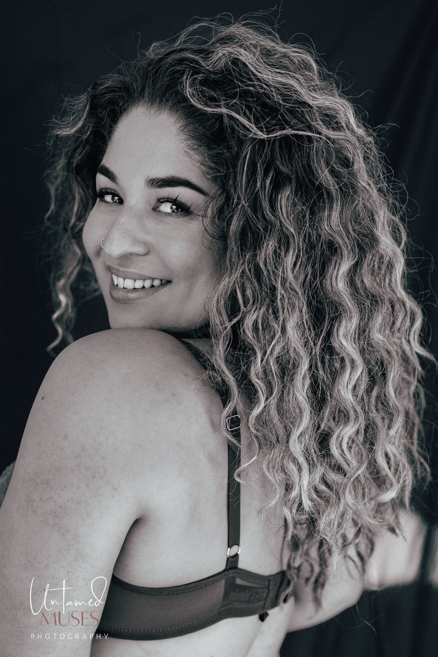 Portrait of beautiful woman in lingerie, turning her head back to look at camera, monochrome. Untamed Muses empowerment