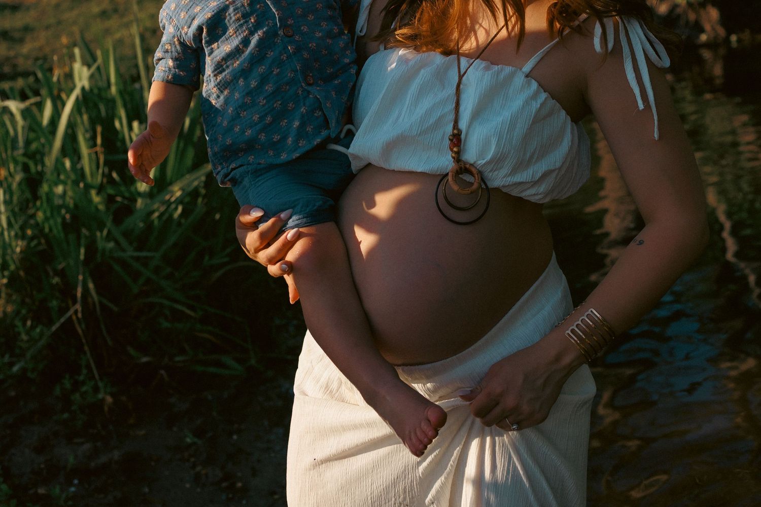 close up detail portrait of pregnant mum holding son in a Norfolk river