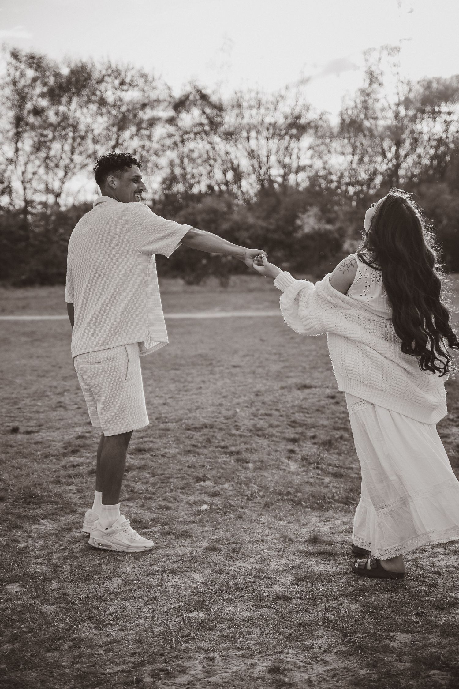 action shot during maternity photoshoot in nature, monochrome, couple dancing