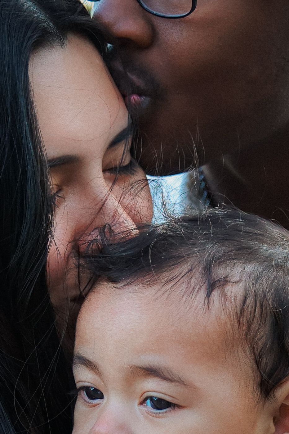 close up portrait of dad kissing mums forehead and mum kissing baby's forehead. interracial family love captures by Untamed Muses ,Thetford