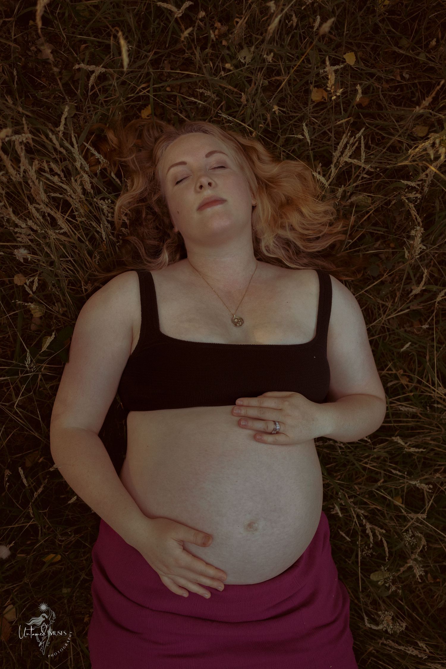 Beautiful low sun evening ,pregnant woman resting on the ground caressing her bump , sensual reclamation, empowerment, natural light