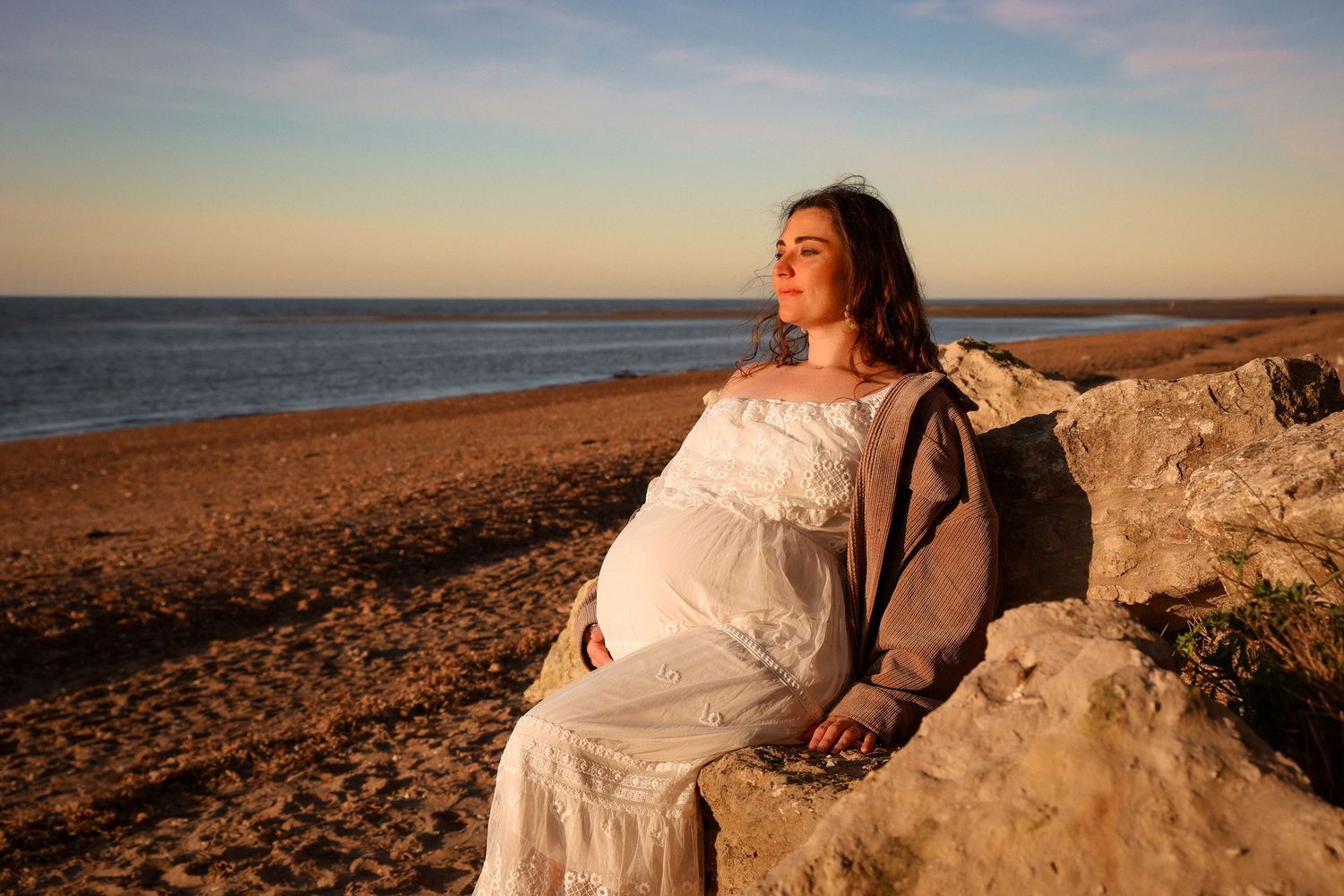 Portrait of a pregnant woman during sunset at the beach, serene and empowered by Untamed Muses photography in Thetford
