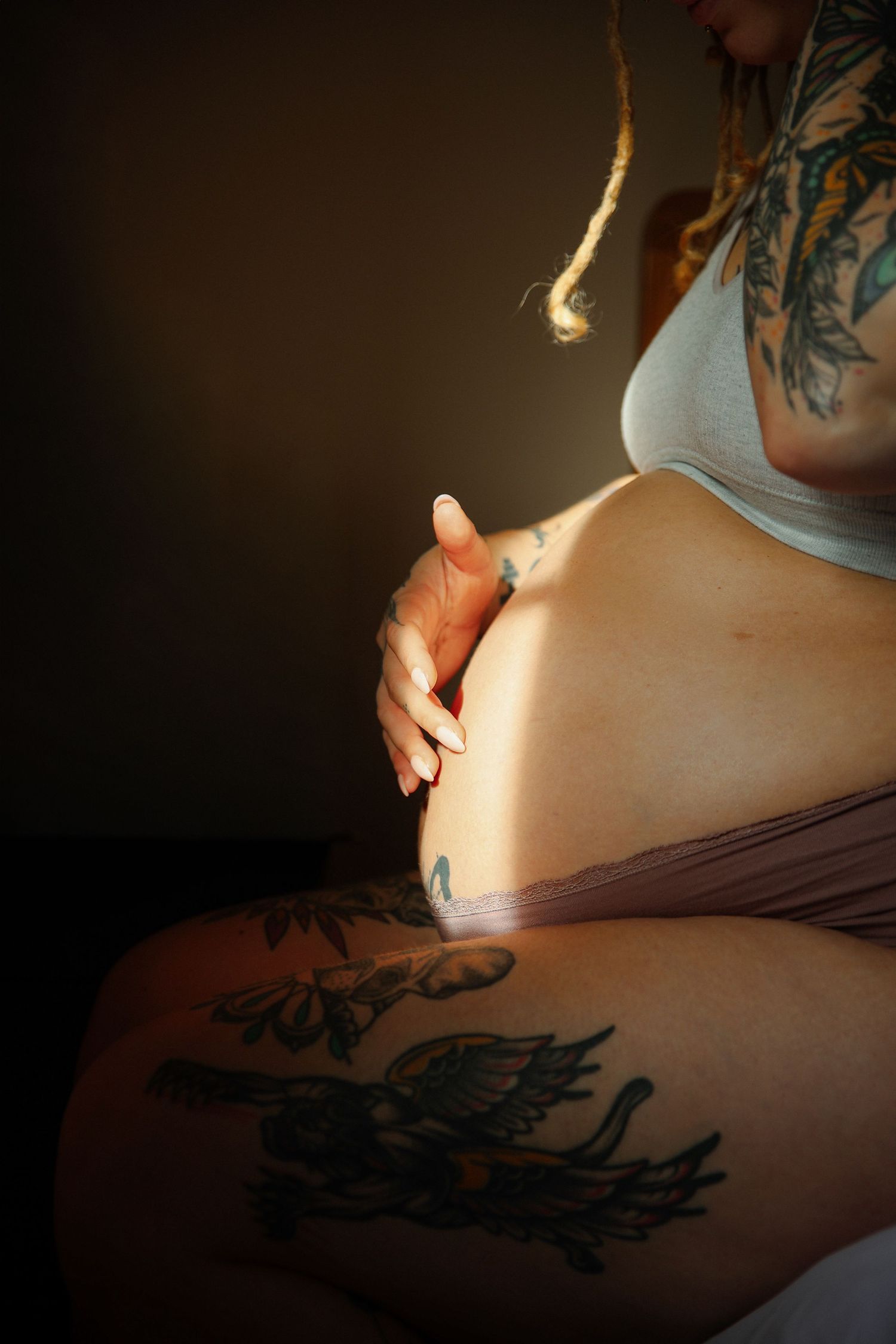 Close up of pregnant bump, sunlight and mums delicately tracing the curve. Authentic maternity photography by Untamed Muses in Norfolk