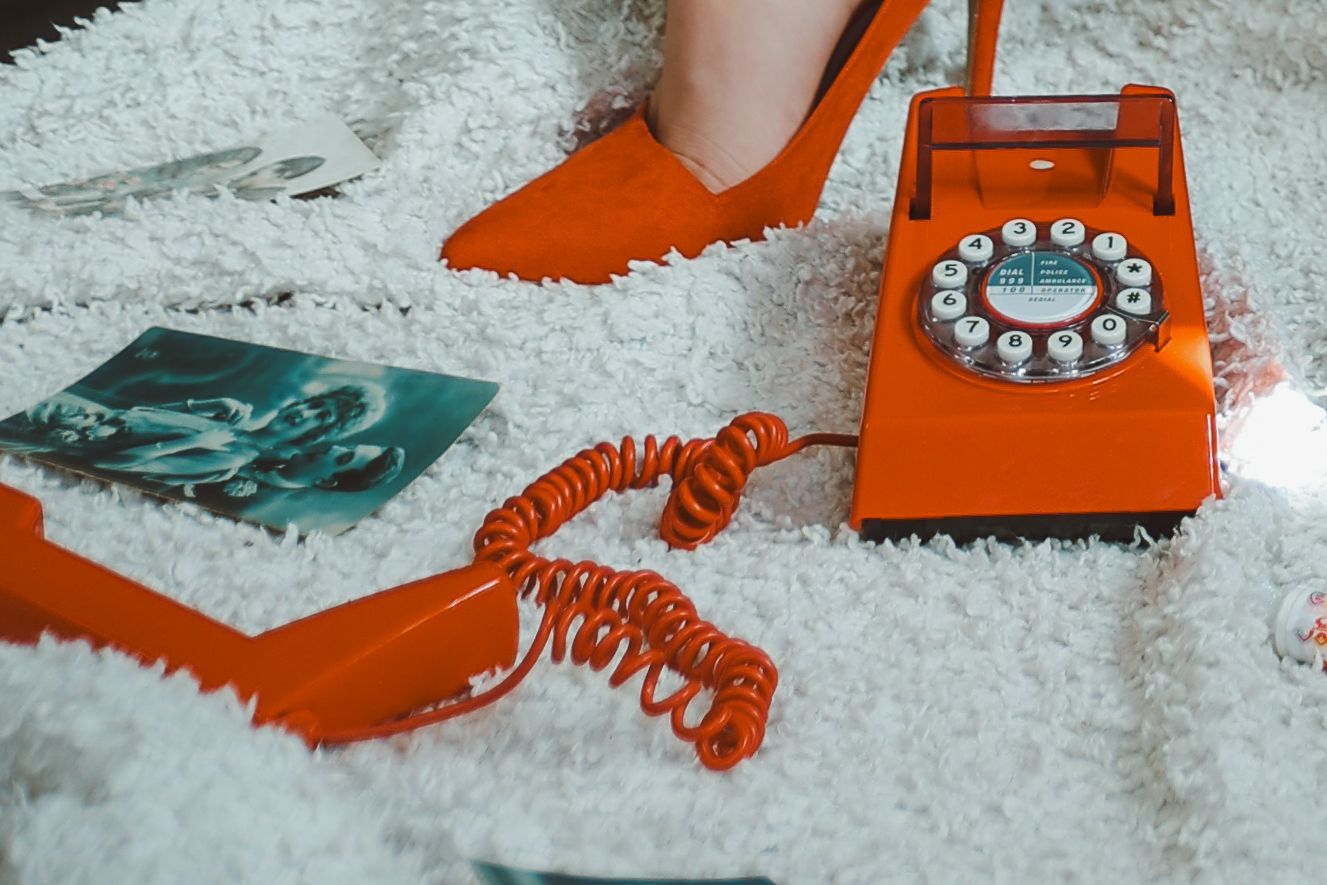 Portrait detail of red retro phone and red high heels and vintage postcards during pin-up themed photoshoot byUntamed Muses