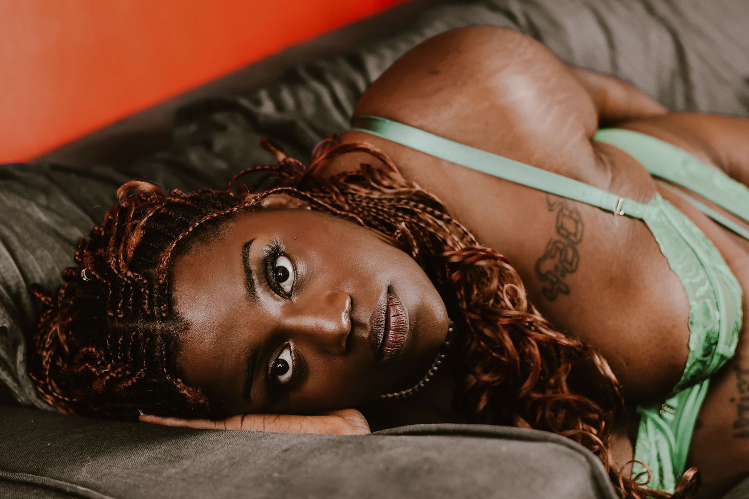 Portrait of beautiful melanated woman laying on her sofa during a boudoir photoshoot at her home in Suffolk by Untamed Muses