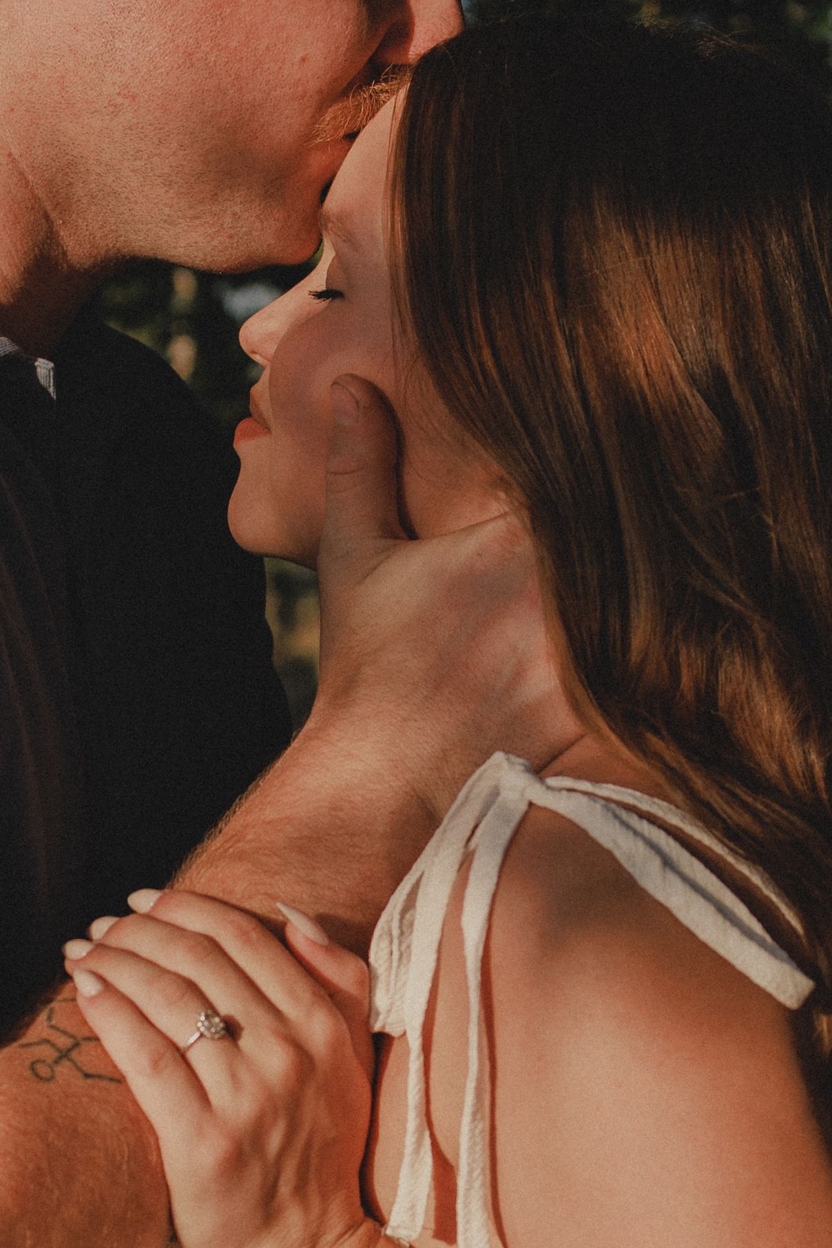 close up portrait of husband kissing wife on the forehead during theirs outdoors maternity photoshoot by untamed muses