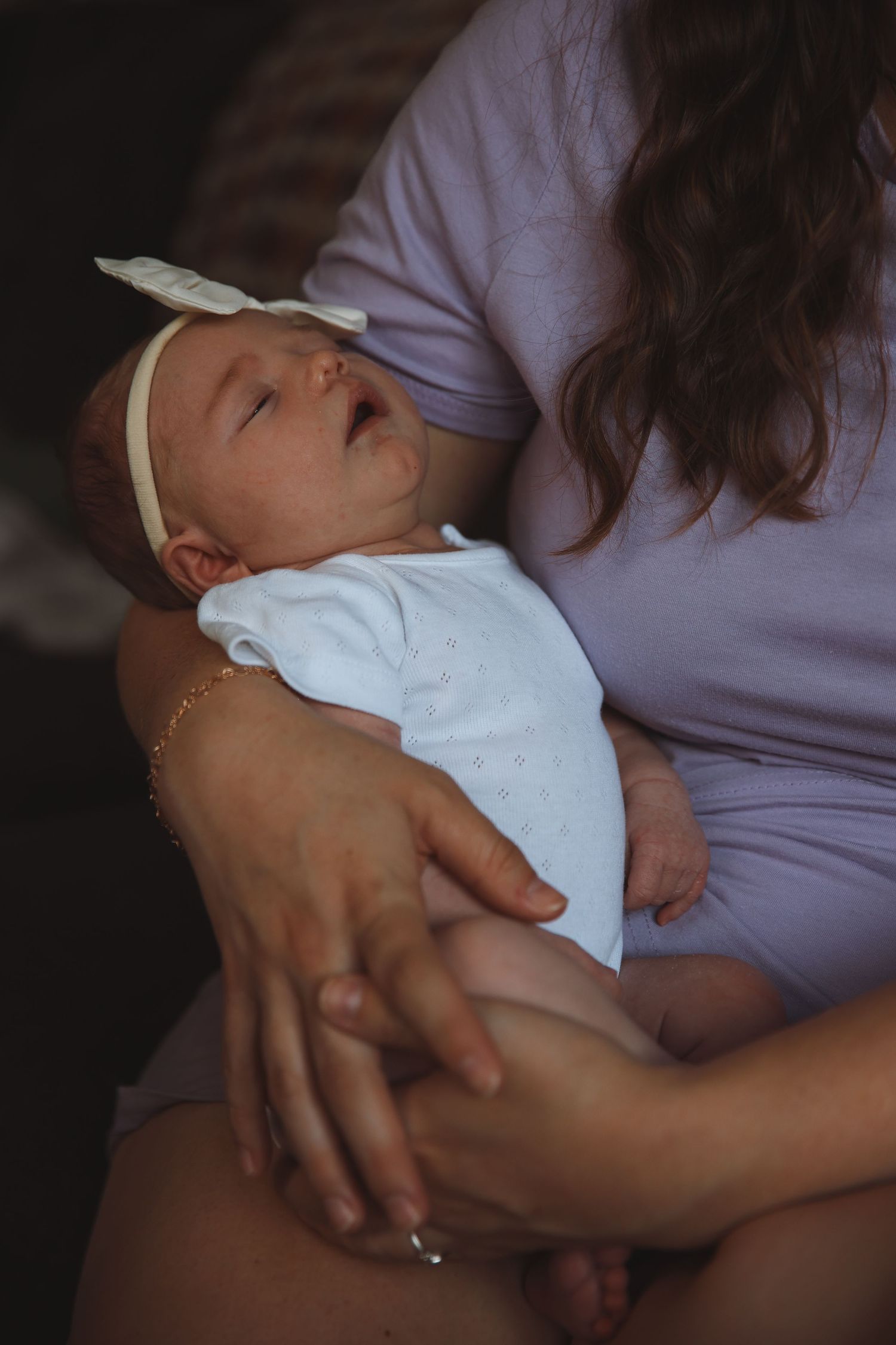 Newborn baby-girl held in mums arms , sleeping peacefully , documenting candid moments and genuine connection, natural newborn photoshoot
