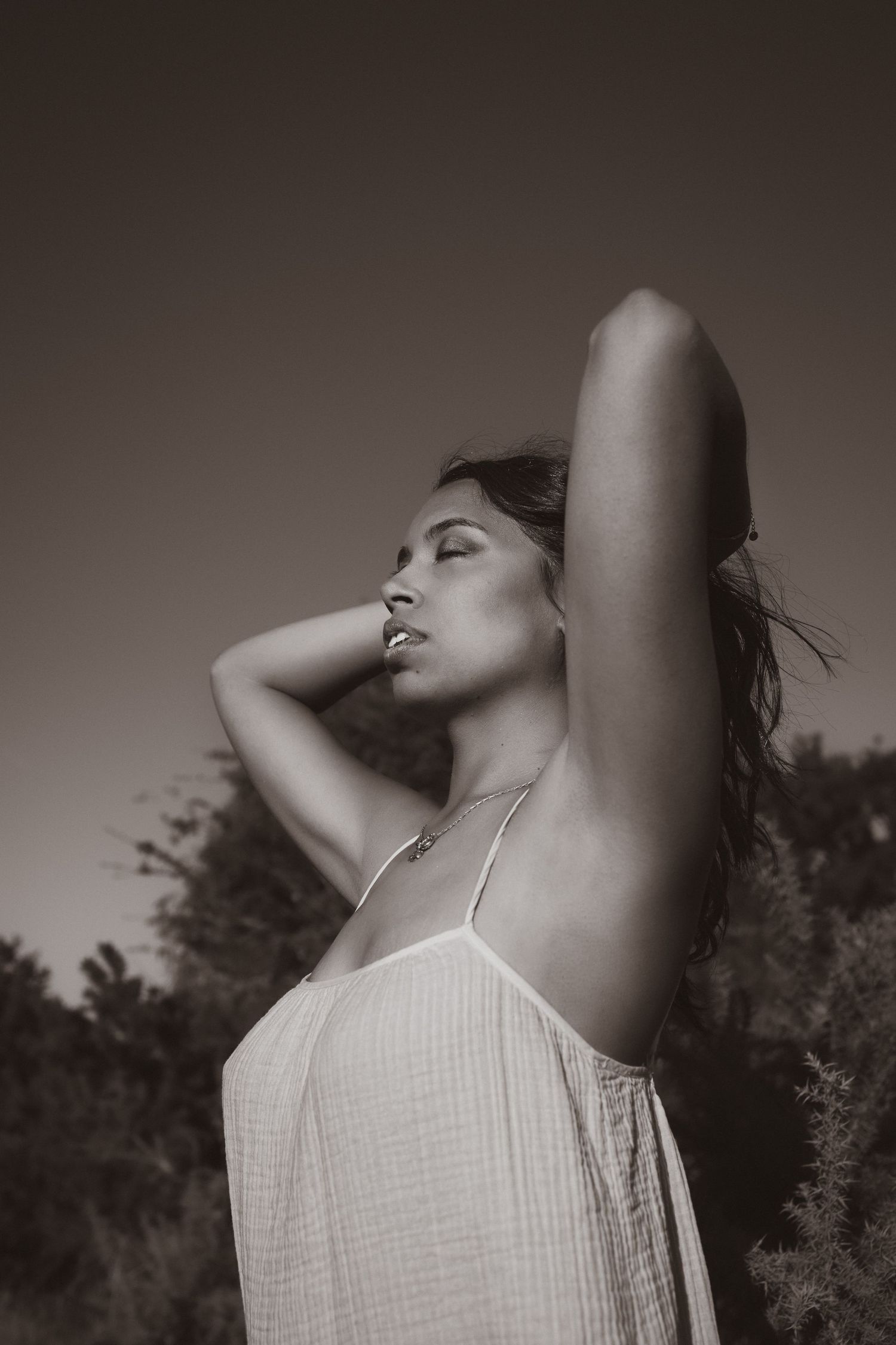 Empowerment photography in Norfolk. Woman amidst tall grass, hair blowing with the wind, female gaze photographer. Monochrome