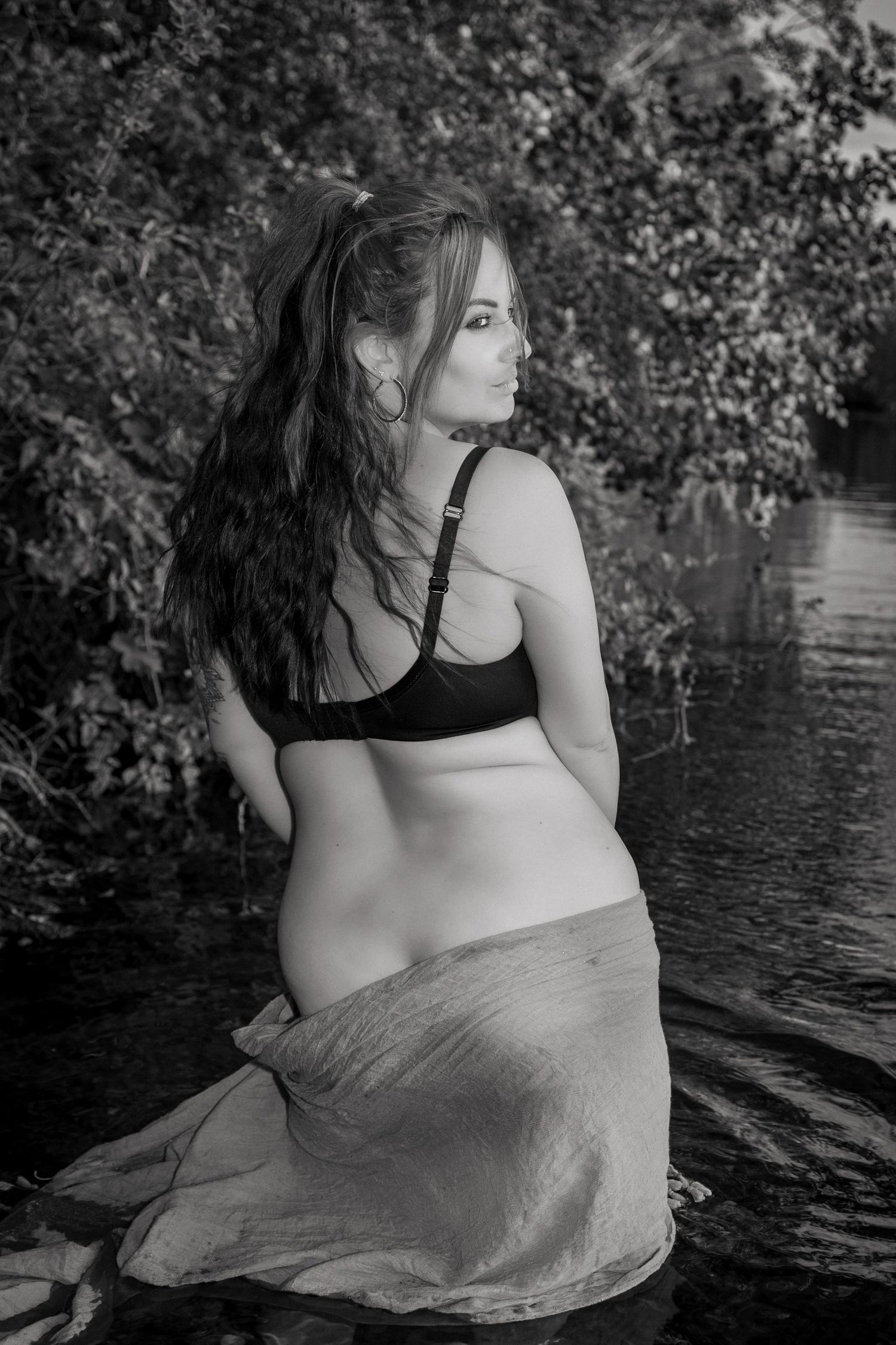 Empowerment in nature photoshoot, monochrome portrait of lady looking back, in the river, Thetford