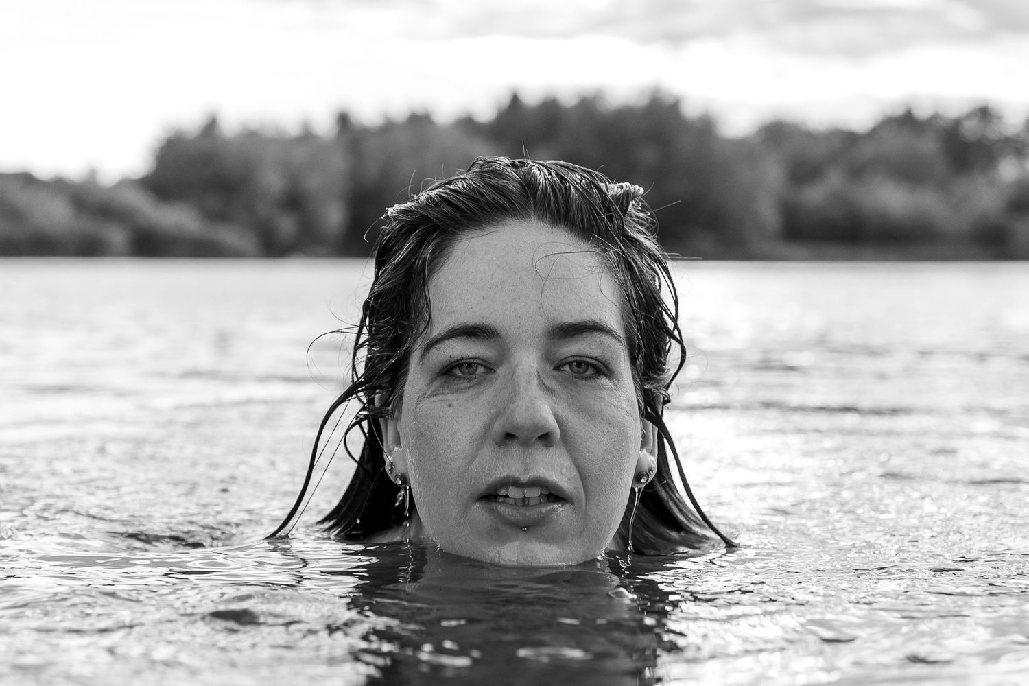 monochrome portrait of woman swimming in a lake, emotive, raw, empowerment photography for women from the female gaze