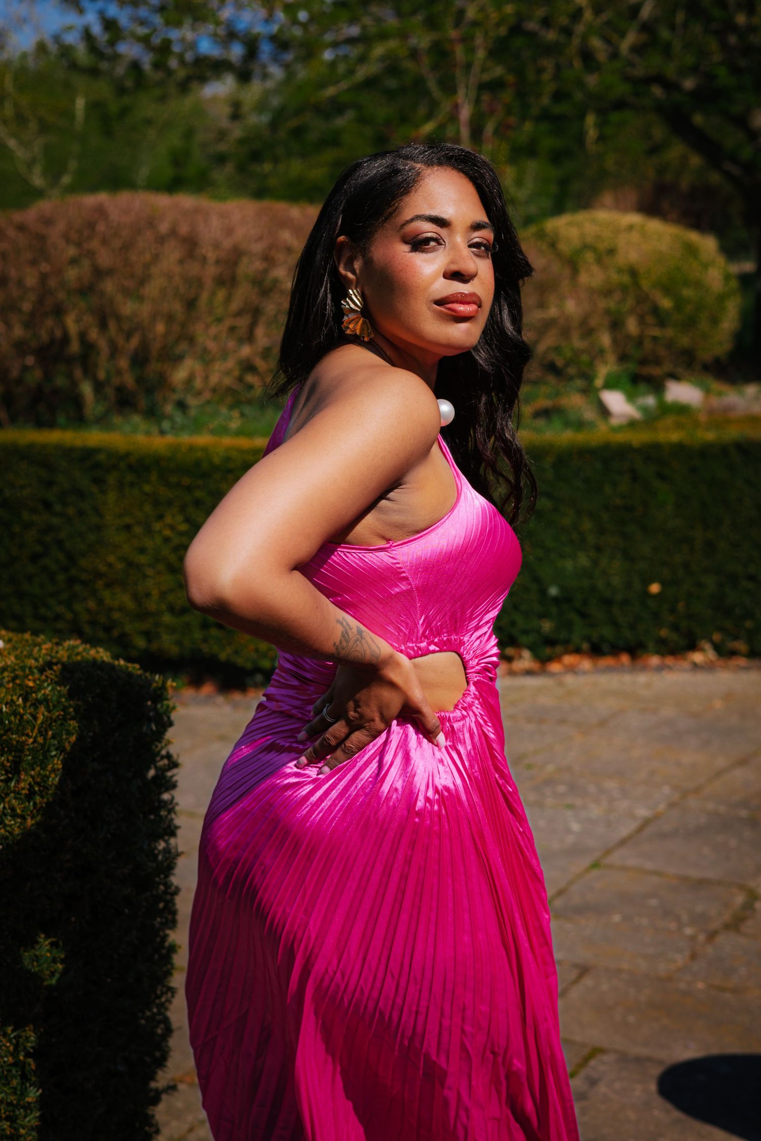 personal branding in the Christchurch mansion garden ,Ipswich.bold colours, cultural fusion, woman in pink dress, looking back, in her power