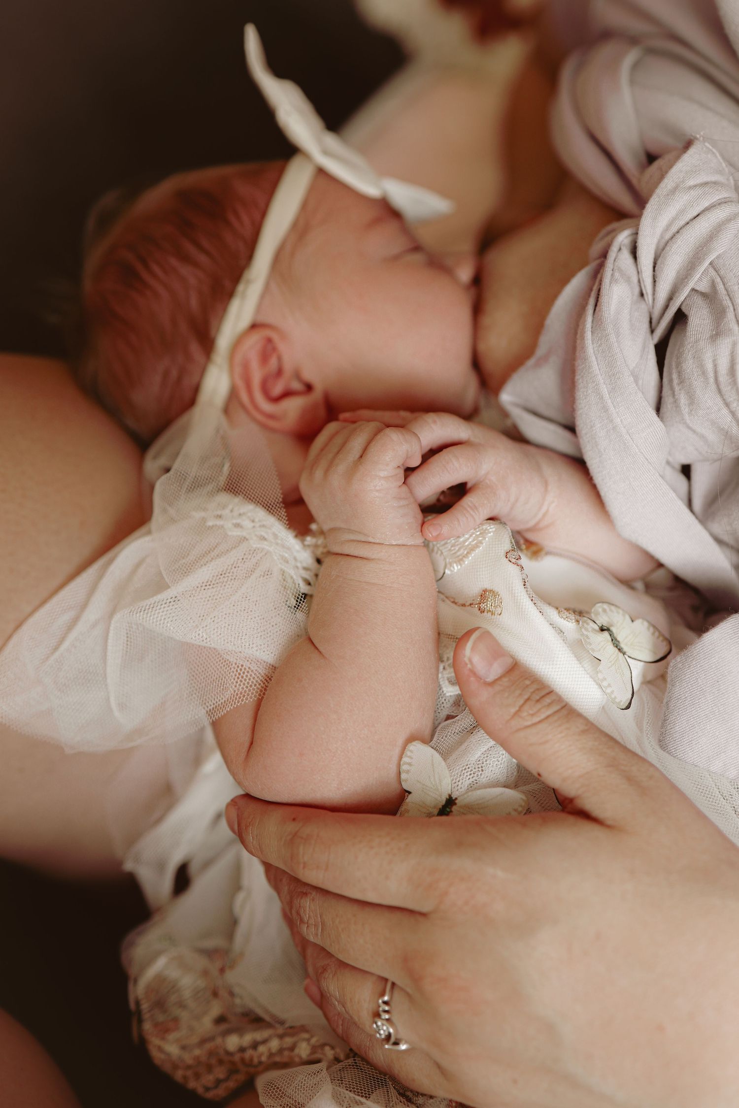 Newborn baby breastfeeding, holding her hands together in the warm, comfort of their home. Natural newborn , candid photography Norfolk