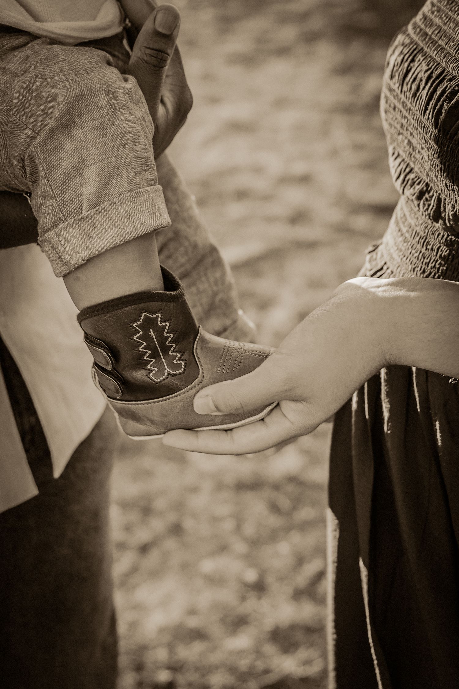 monochrome close up portrait of baby cowboy boots held may loving parents in a gorgeous outdoor location in Thetford