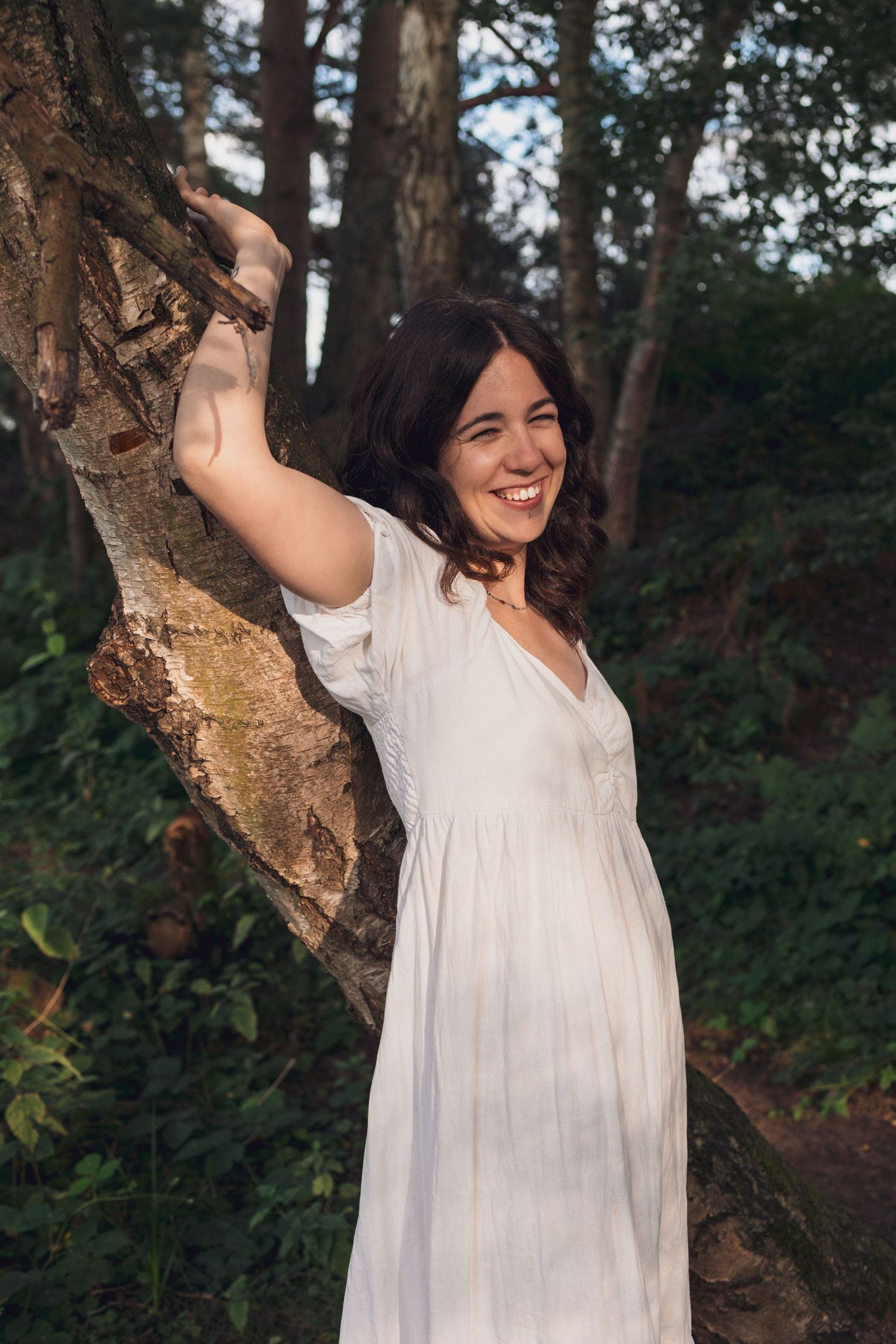 Natural light, colour, empowerment boudoir, wild in nature, divine feminine, beautiful, smiling woman in white dress, resting on tree