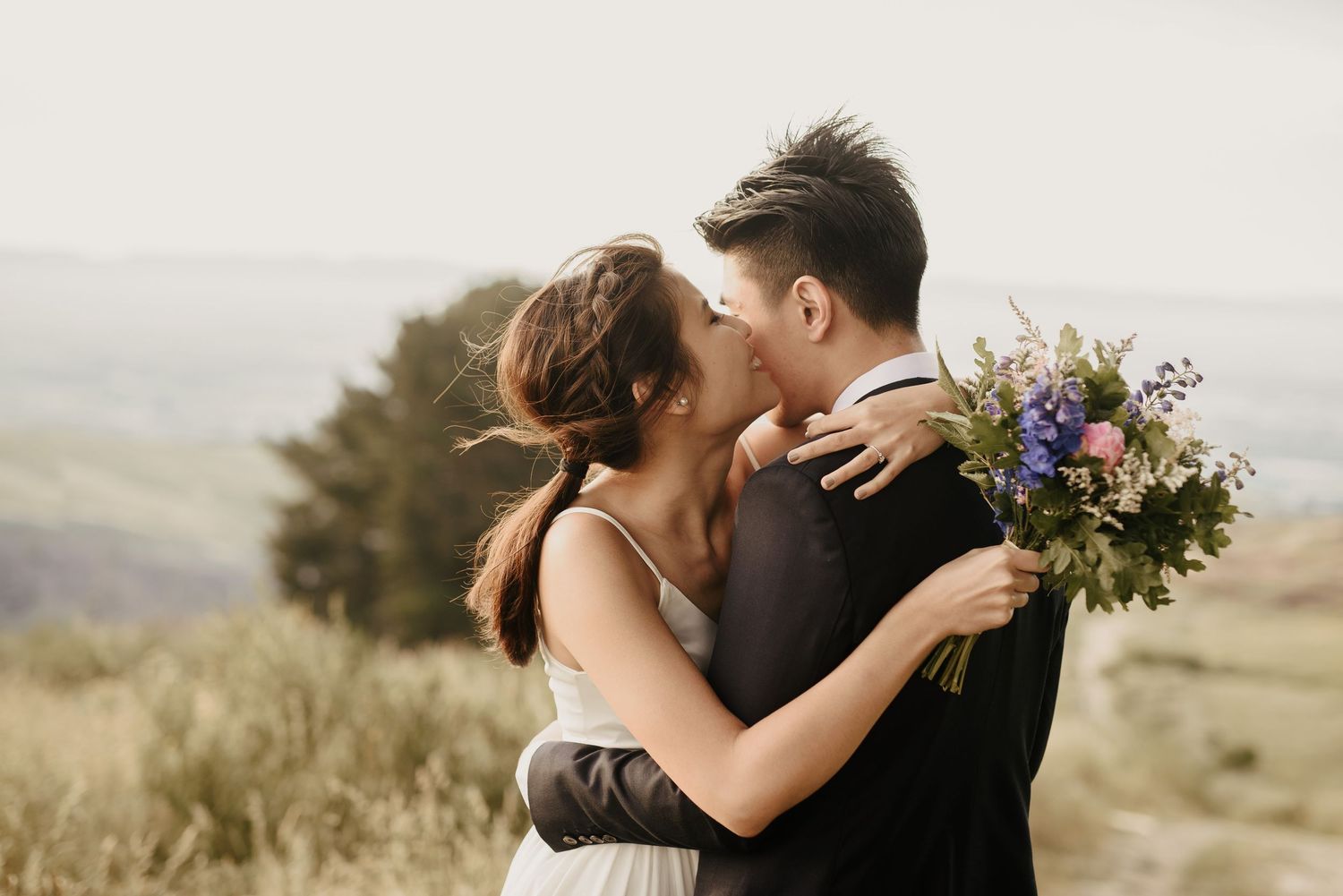 Couple embracing on Port Hills for their wedding photos with flowers