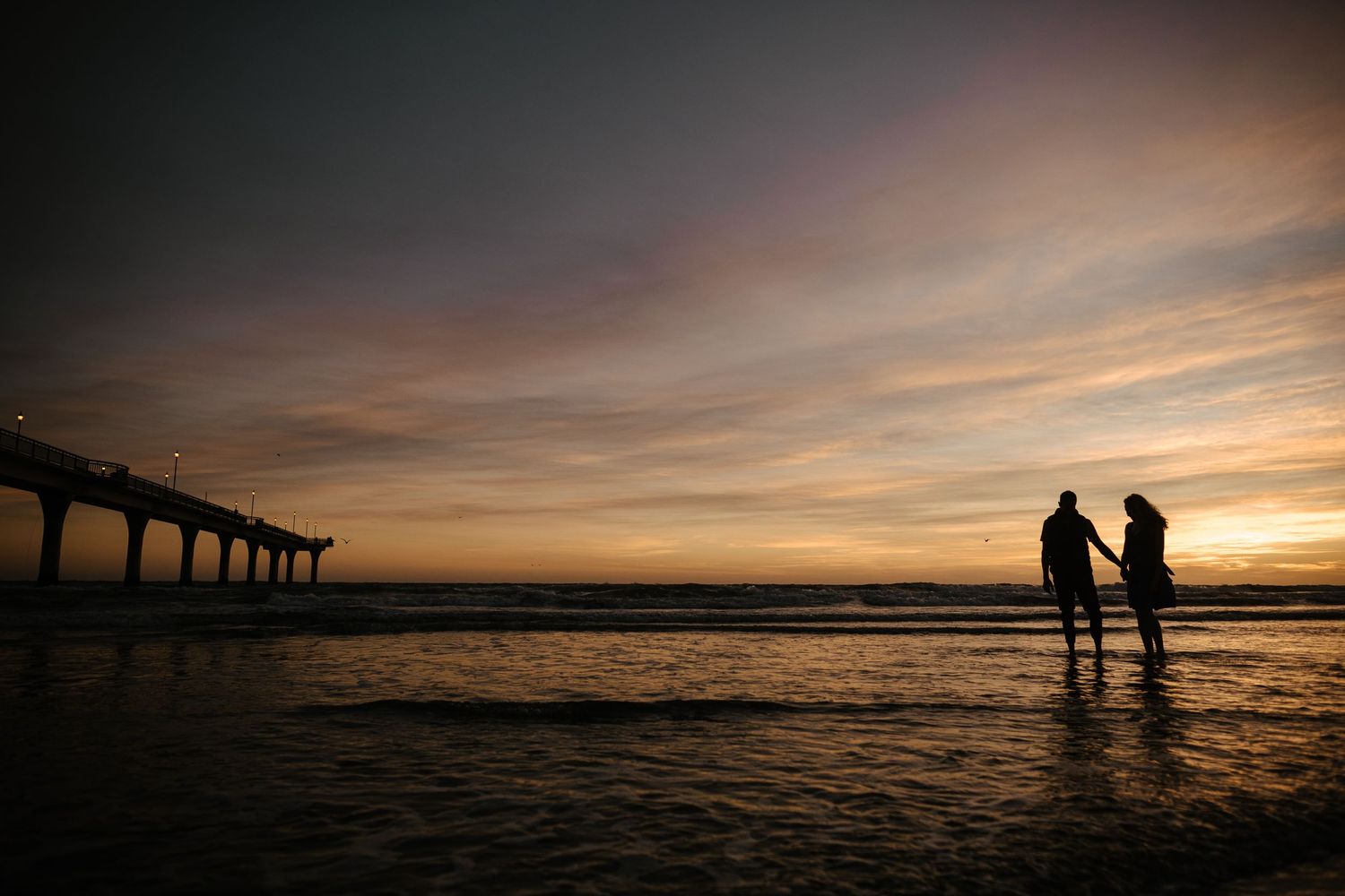 Silhouette by New Brighton pier — morning sunrise engagement photography.