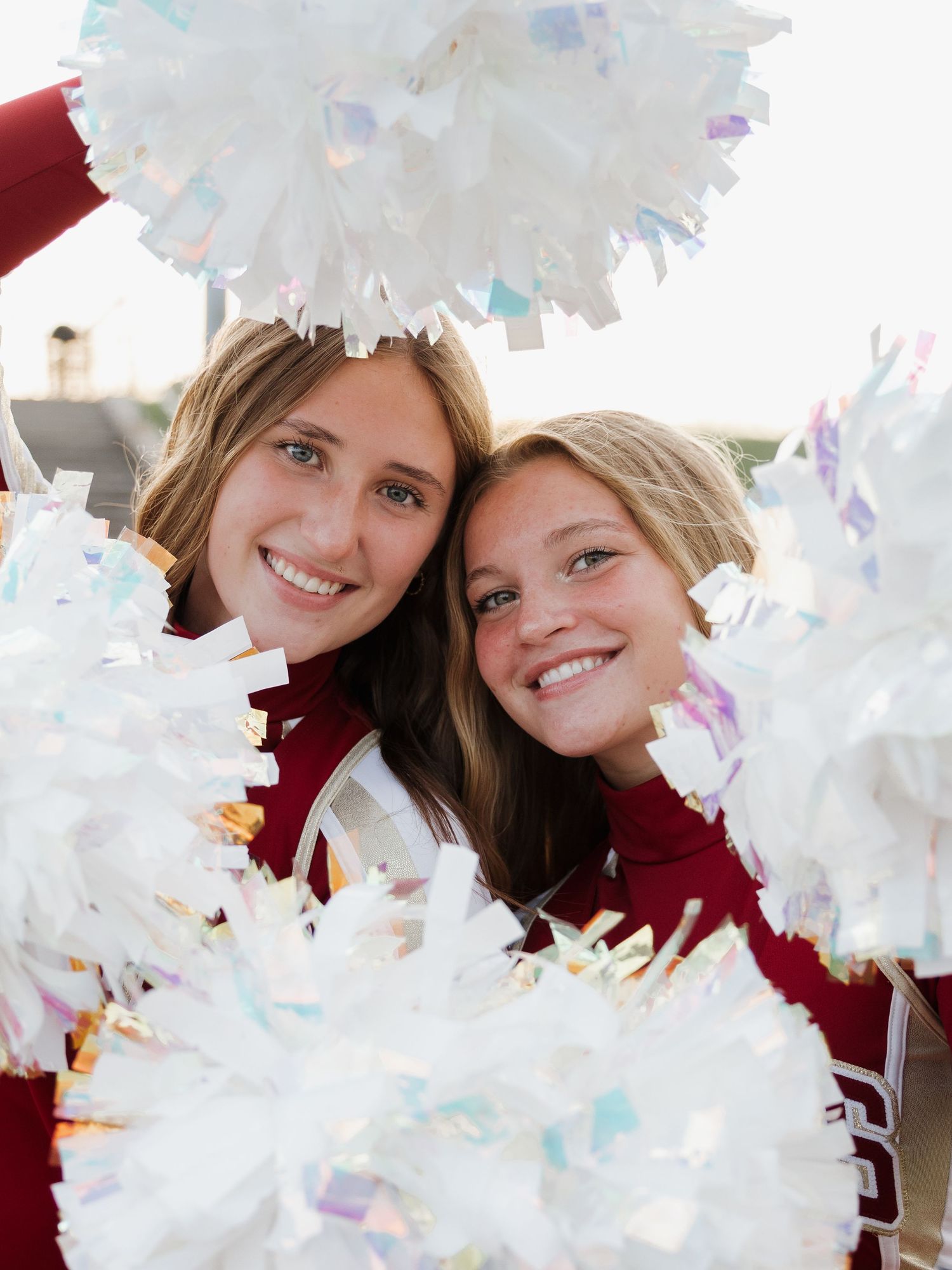 two cheerleaders smiling with poms