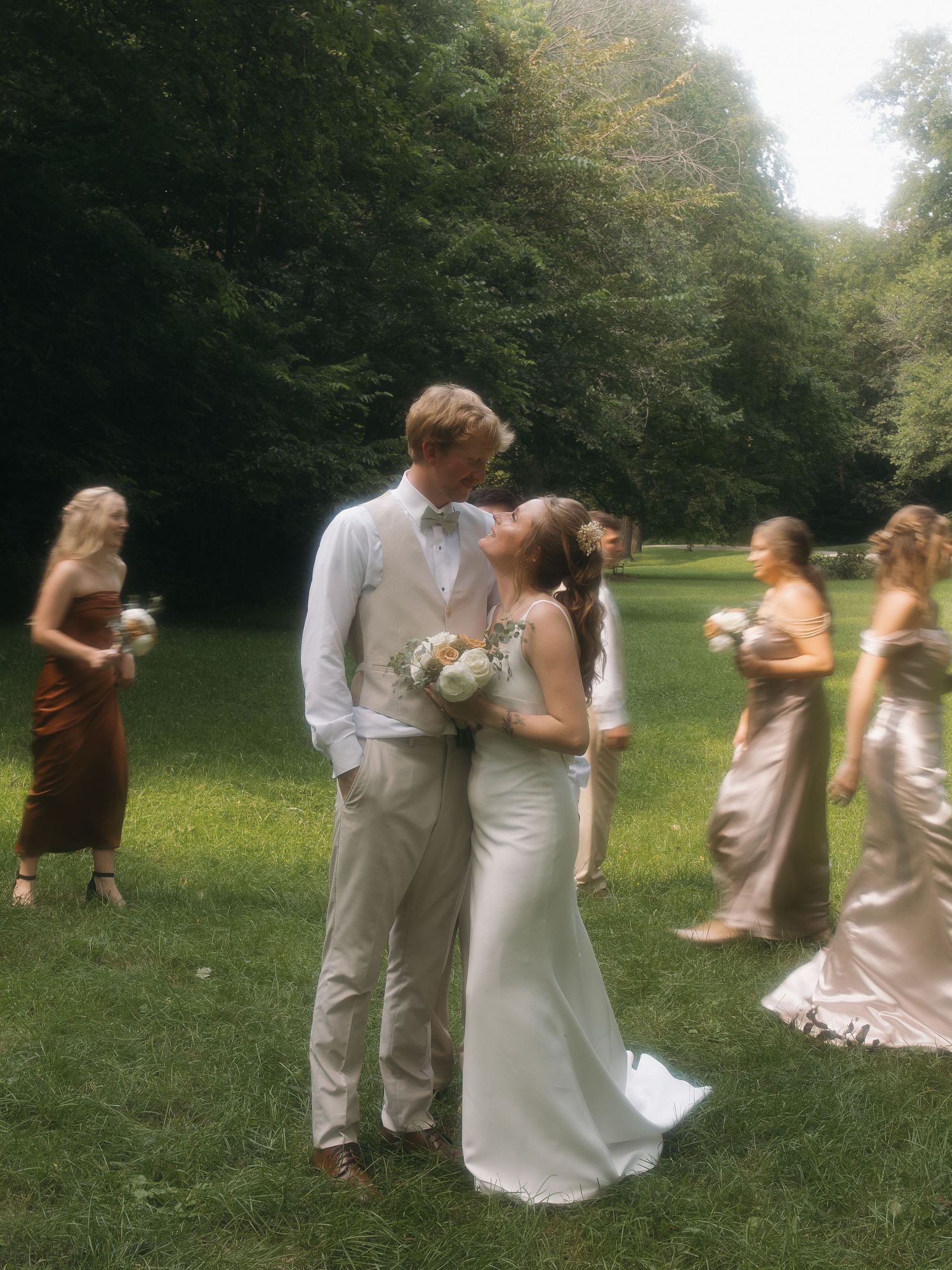 bride and groom focused in soft glow with wedding party moving around them