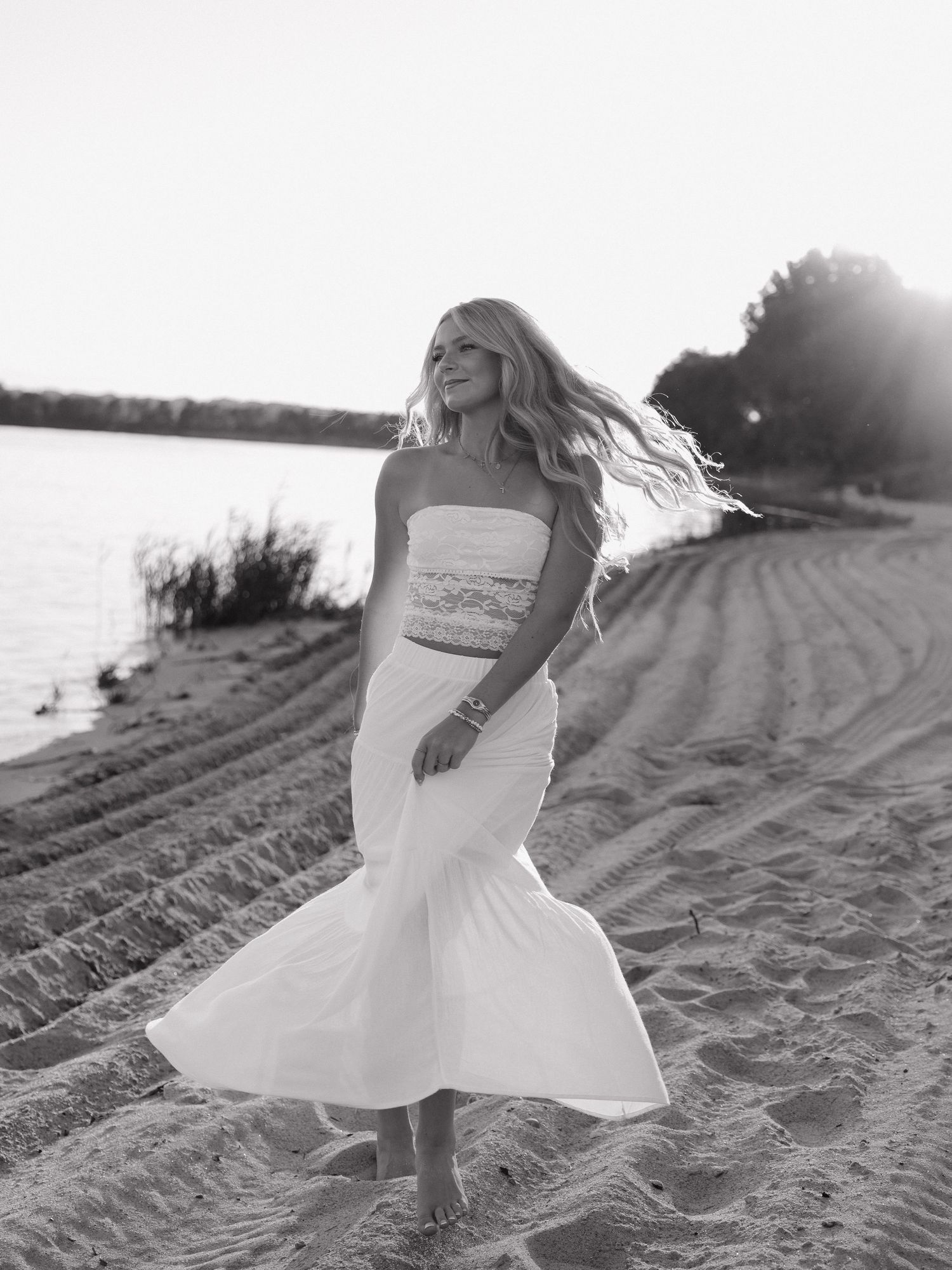 graduate spins in candid movement on a beach