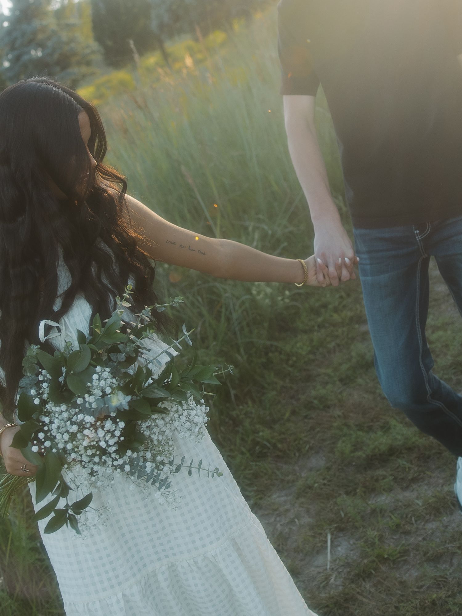 couple holds hands in golden hour lighting
