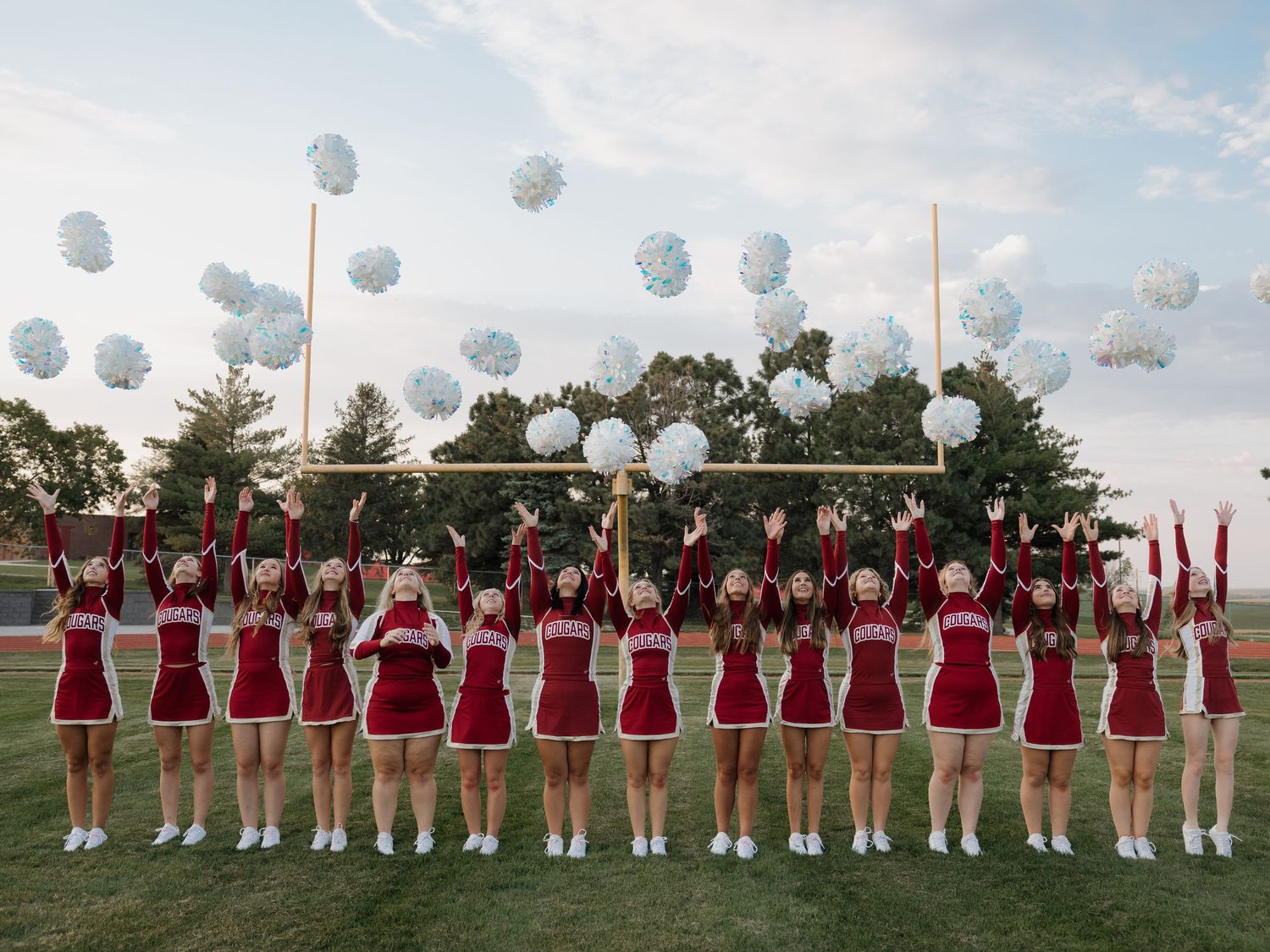 cheer team throwing poms to a colorful sky