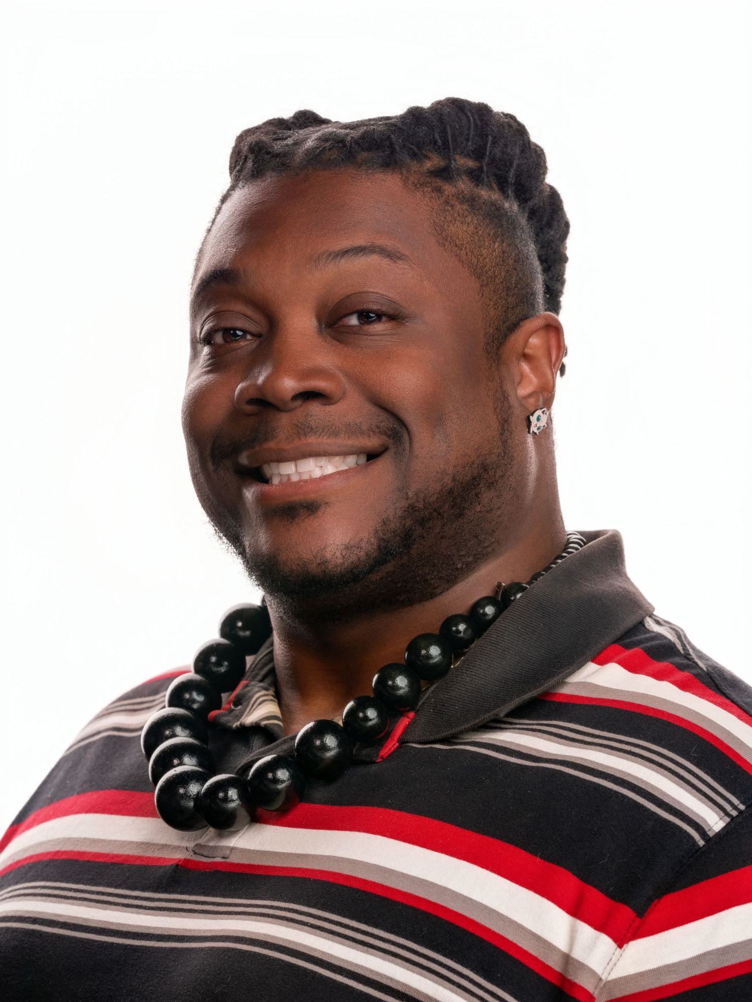 Professional headshot of person wearing striped shirt and beaded necklace with braided hairstyle.