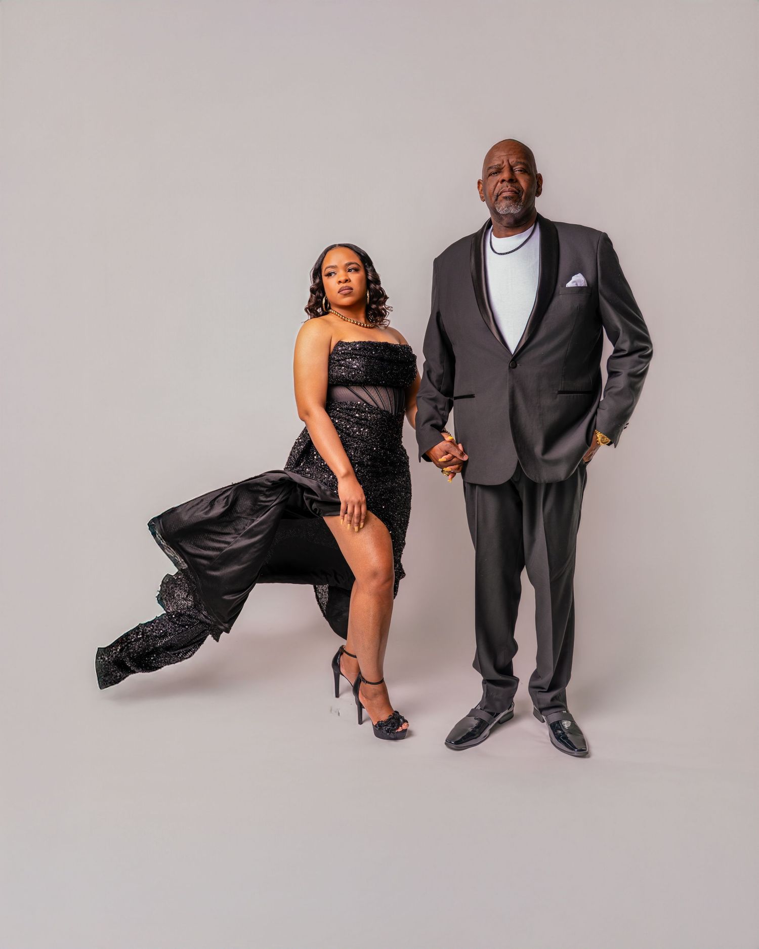 A couple in formal attire poses together against a gray backdrop in a series of artistic dance-inspired portraits.