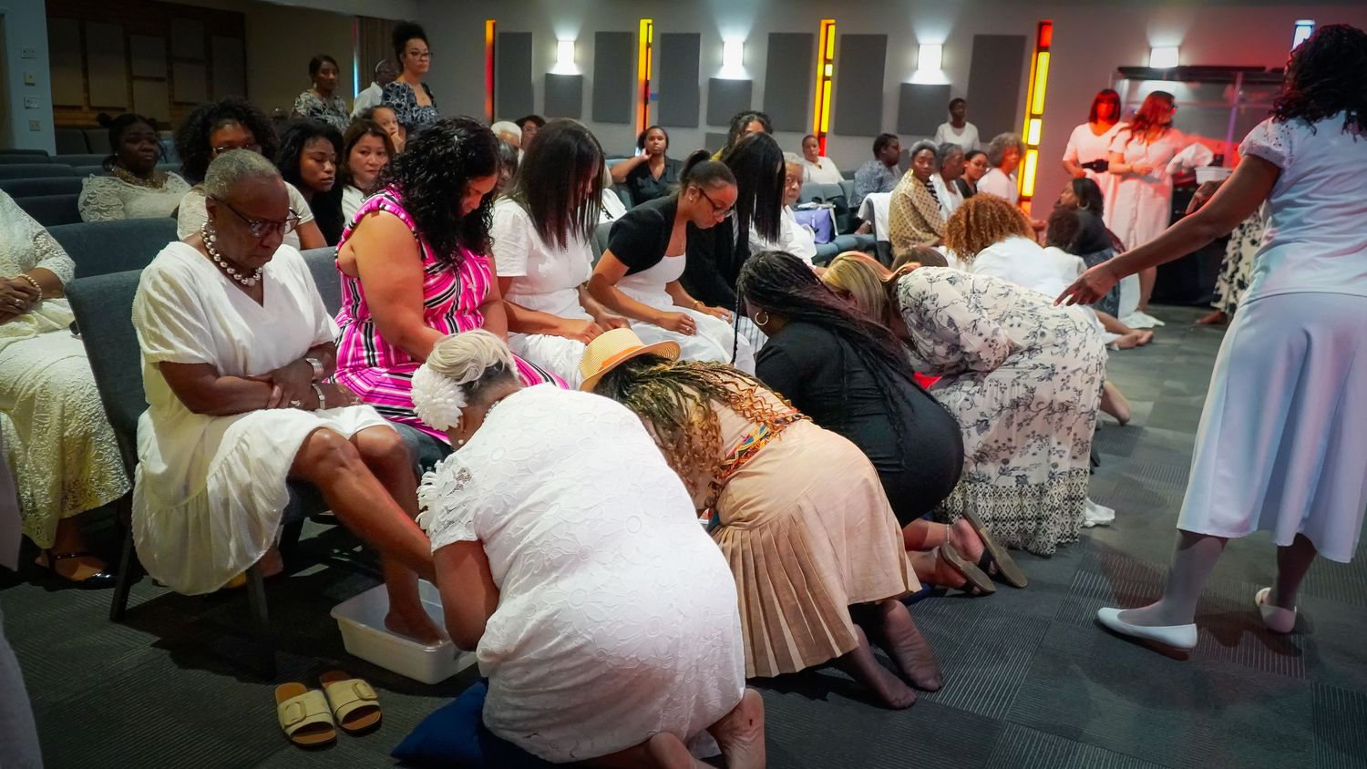 Congregation members engage in prayer during an emotional church service with colorful lighting.