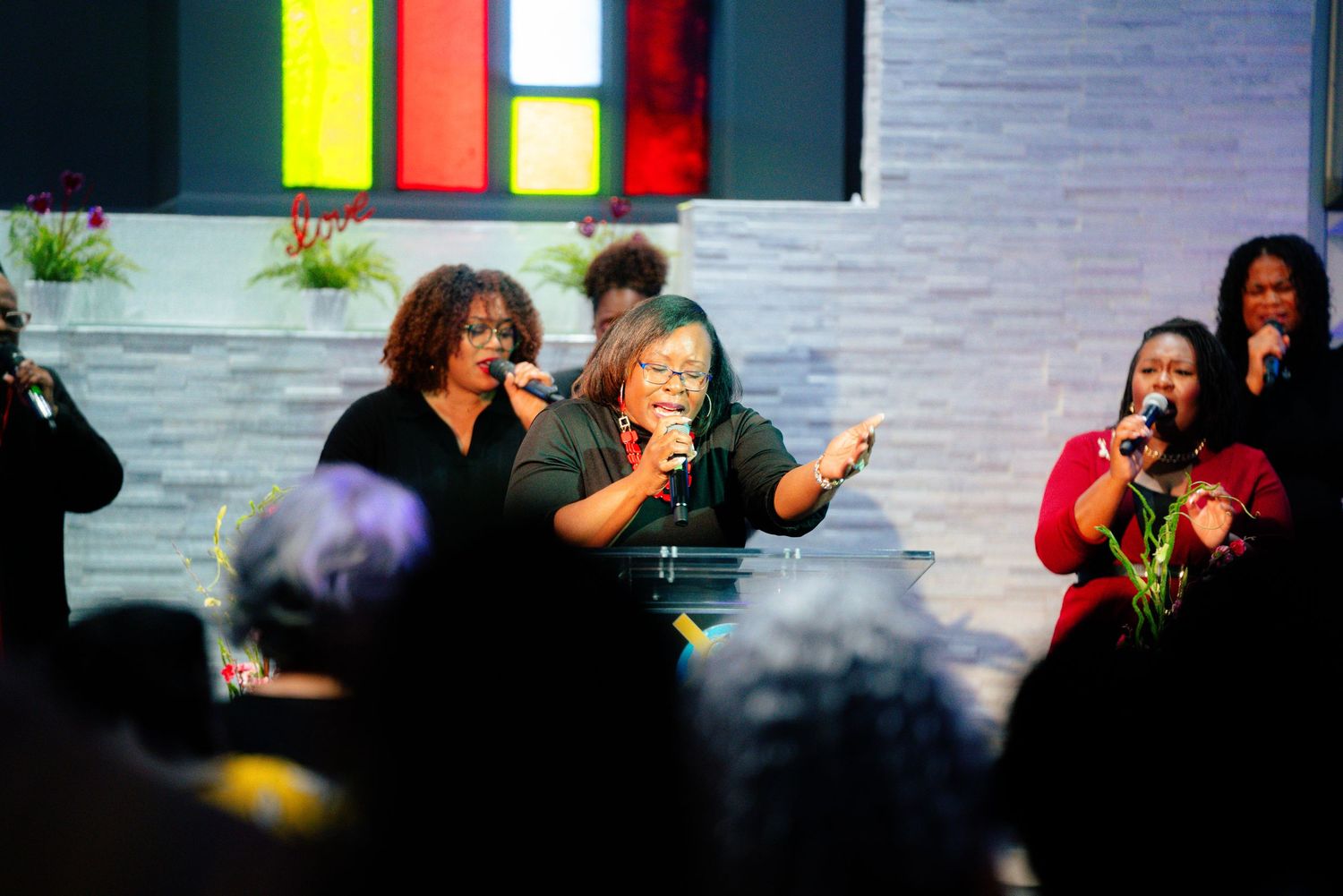 A group performs enthusiastically on stage with colorful lighting and decorative elements in the background.