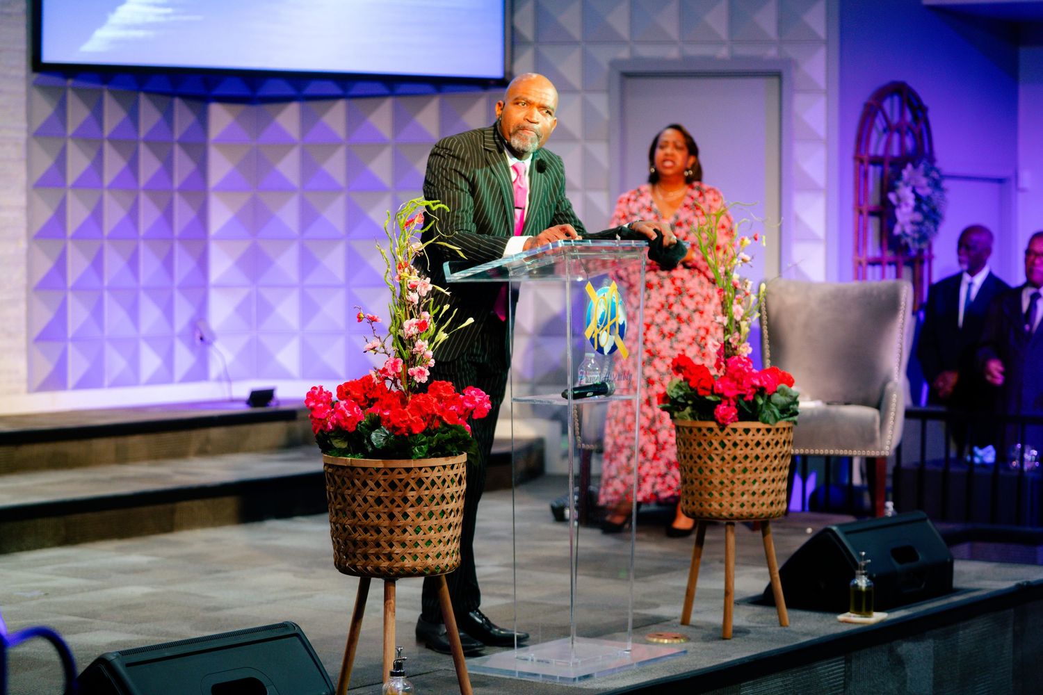 A panel discussion setup with purple lighting and floral decorations on stage.