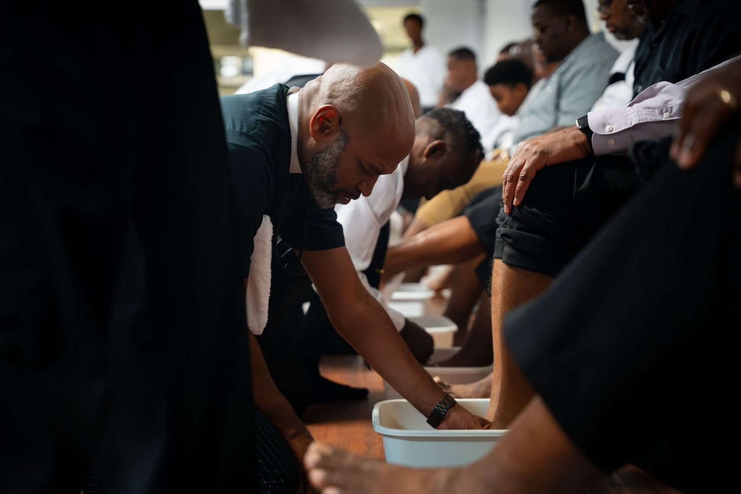 A spiritual gathering shows people bowing their heads in prayer around a table.