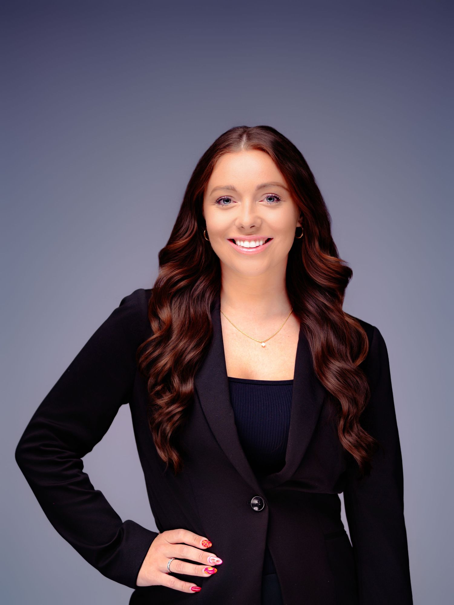 Corporate portrait showing professional attire with a black blazer and styled wavy hair.